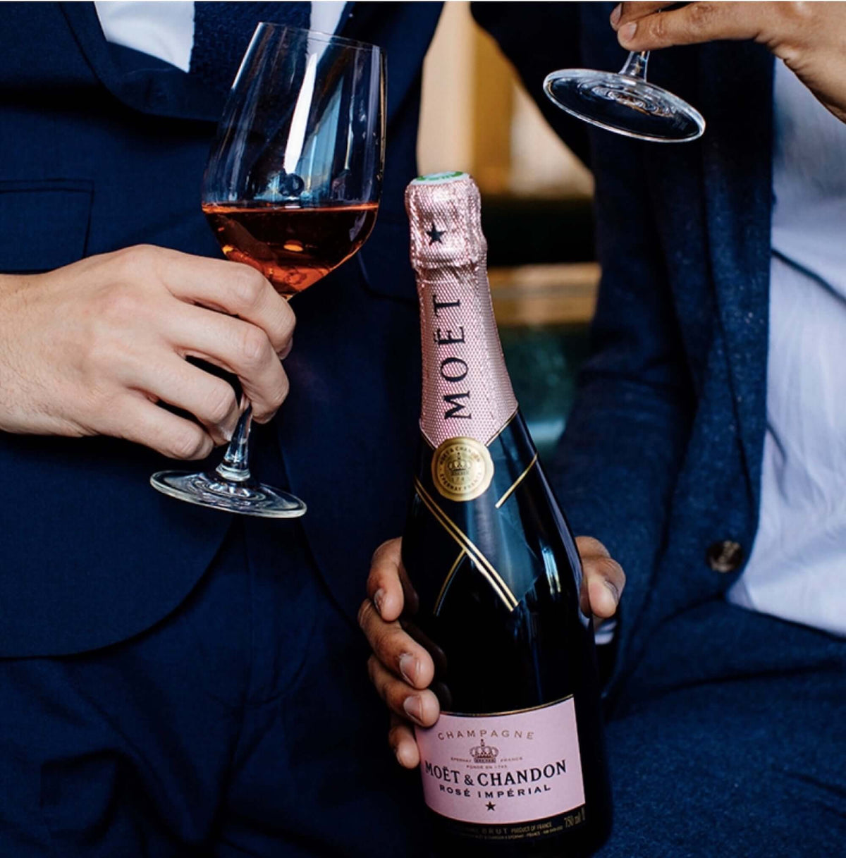 Two people toasting with glasses of Moët & Chandon Rosé Impérial champagne bottle in hand.