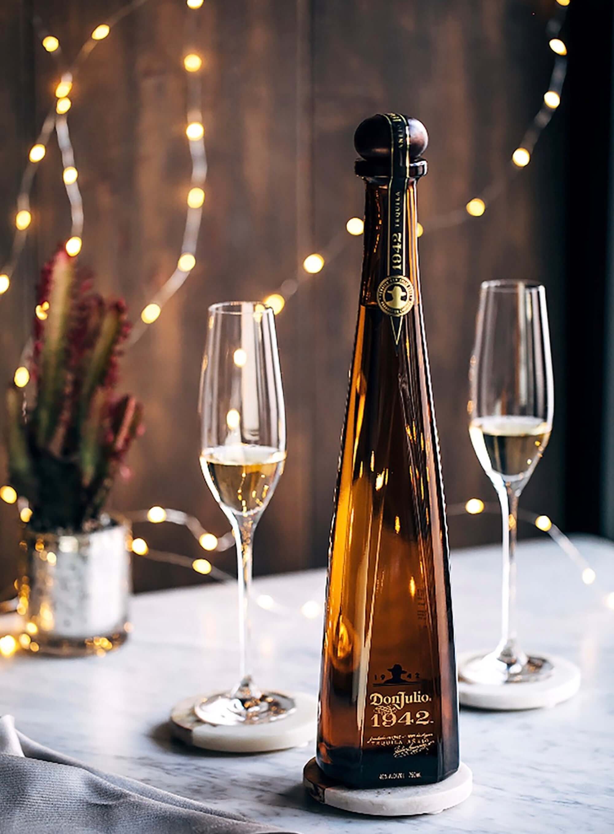 Don Julio Añejo 1942 Tequila bottle with flutes and festive lights, showcasing luxury and craftsmanship