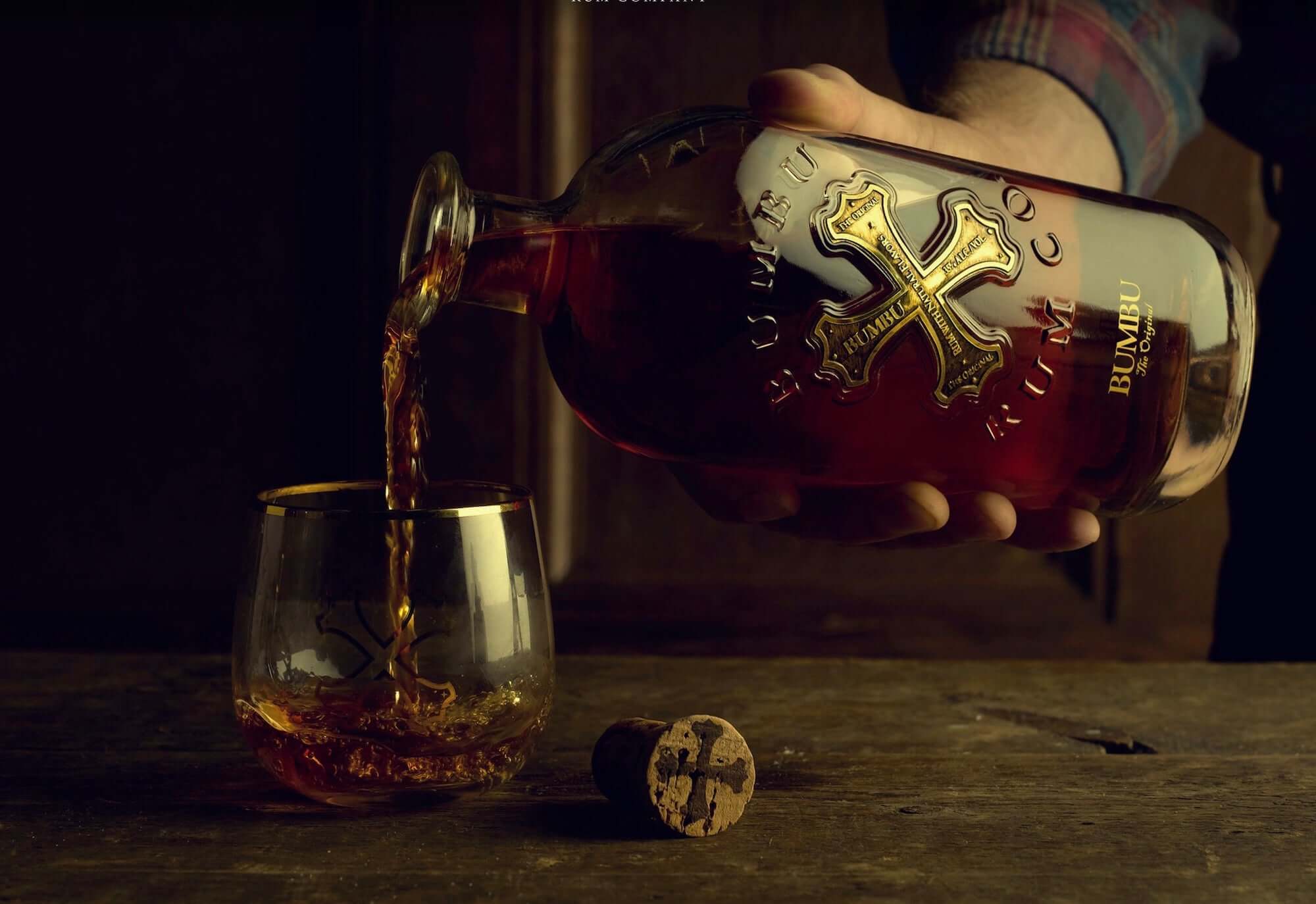 Pouring Bumbu The Original rum into a glass, showcasing its rich color and craftsmanship from Barbados.