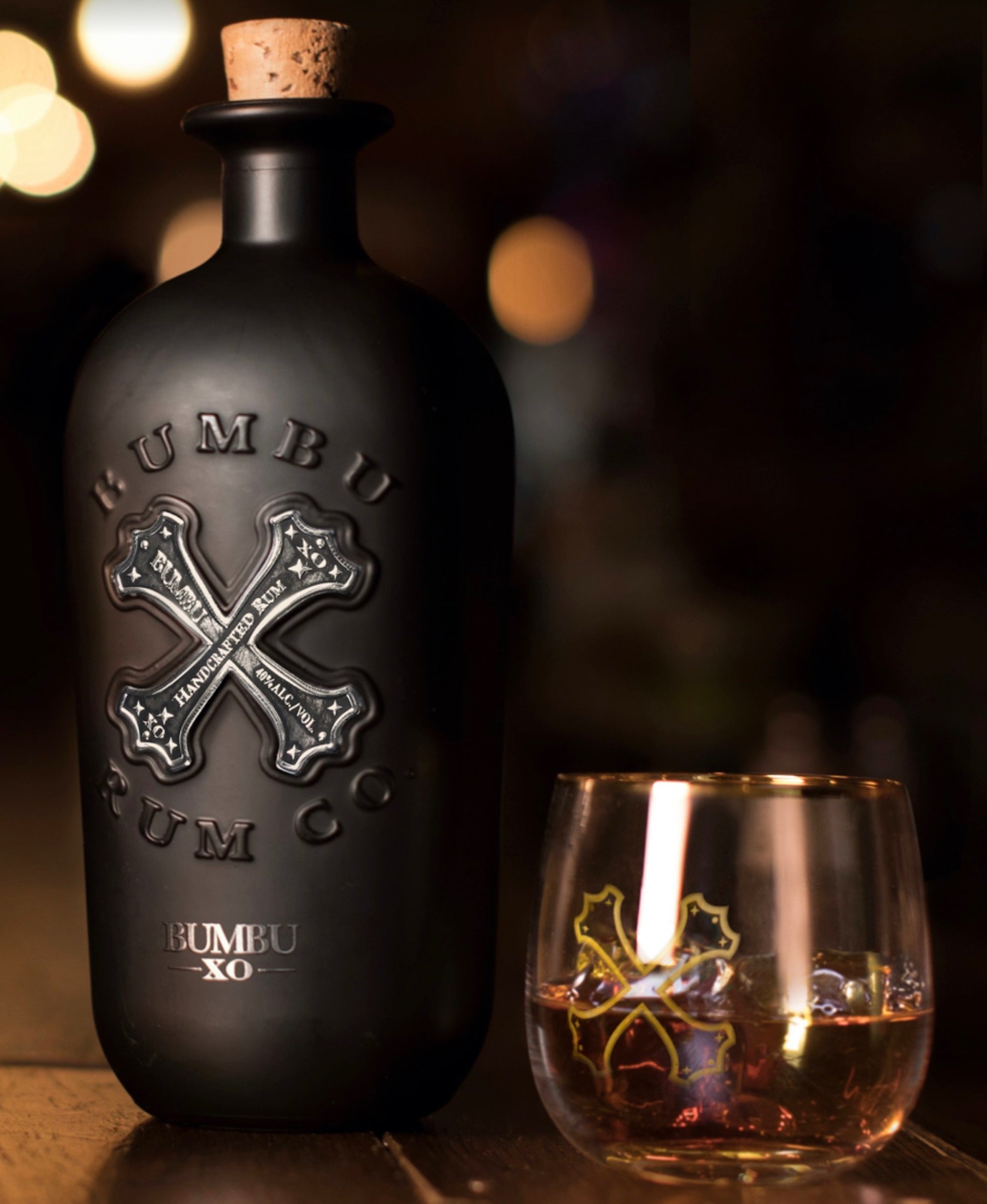 Bumbu XO Rum bottle with cork beside a glass of amber rum, illustrating its richness and craftsmanship.