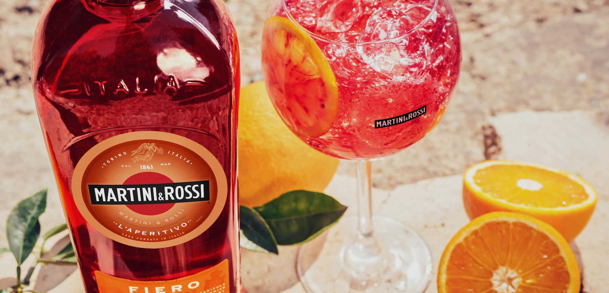 Martini and Rossi Fiero Vermouth bottle beside a refreshing cocktail garnished with orange, highlighting bold, citrus flavors.