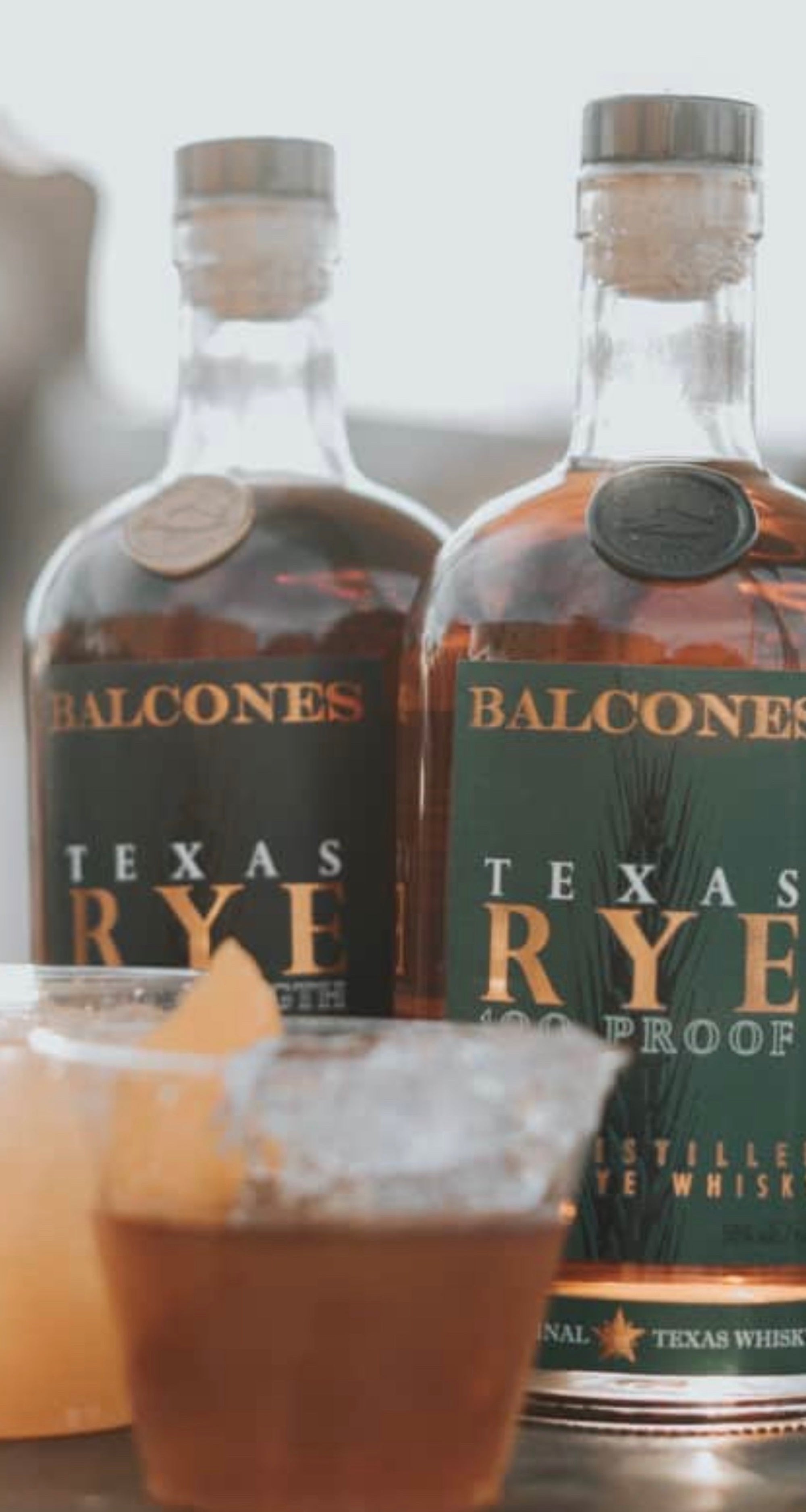 Balcones Texas Rye 100 Proof bottles with a glass of whiskey, showcasing rich flavors and craftsmanship.