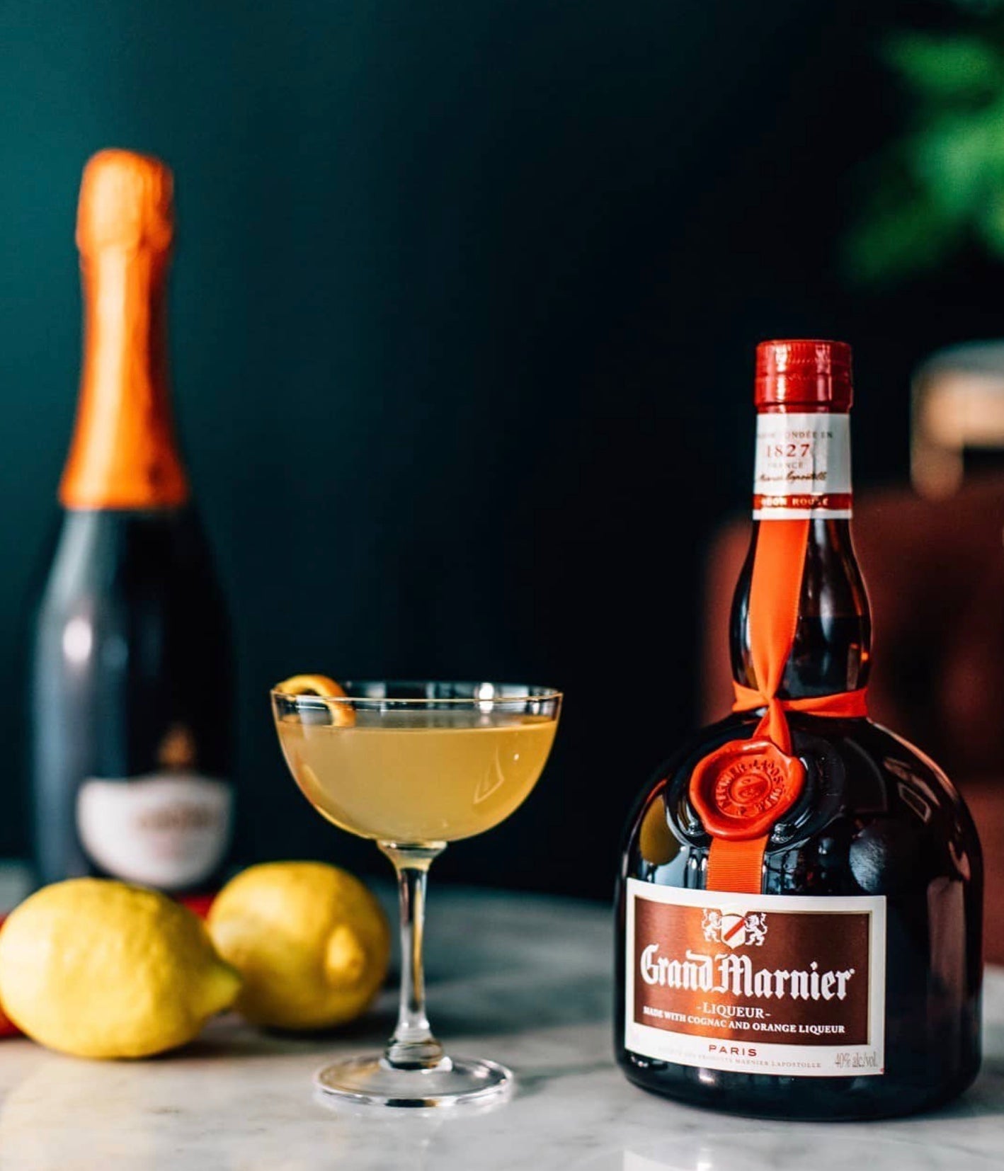 Grand Marnier bottle with a cocktail and fresh lemons on a marble table, showcasing the liqueur's unique blending of orange and cognac.