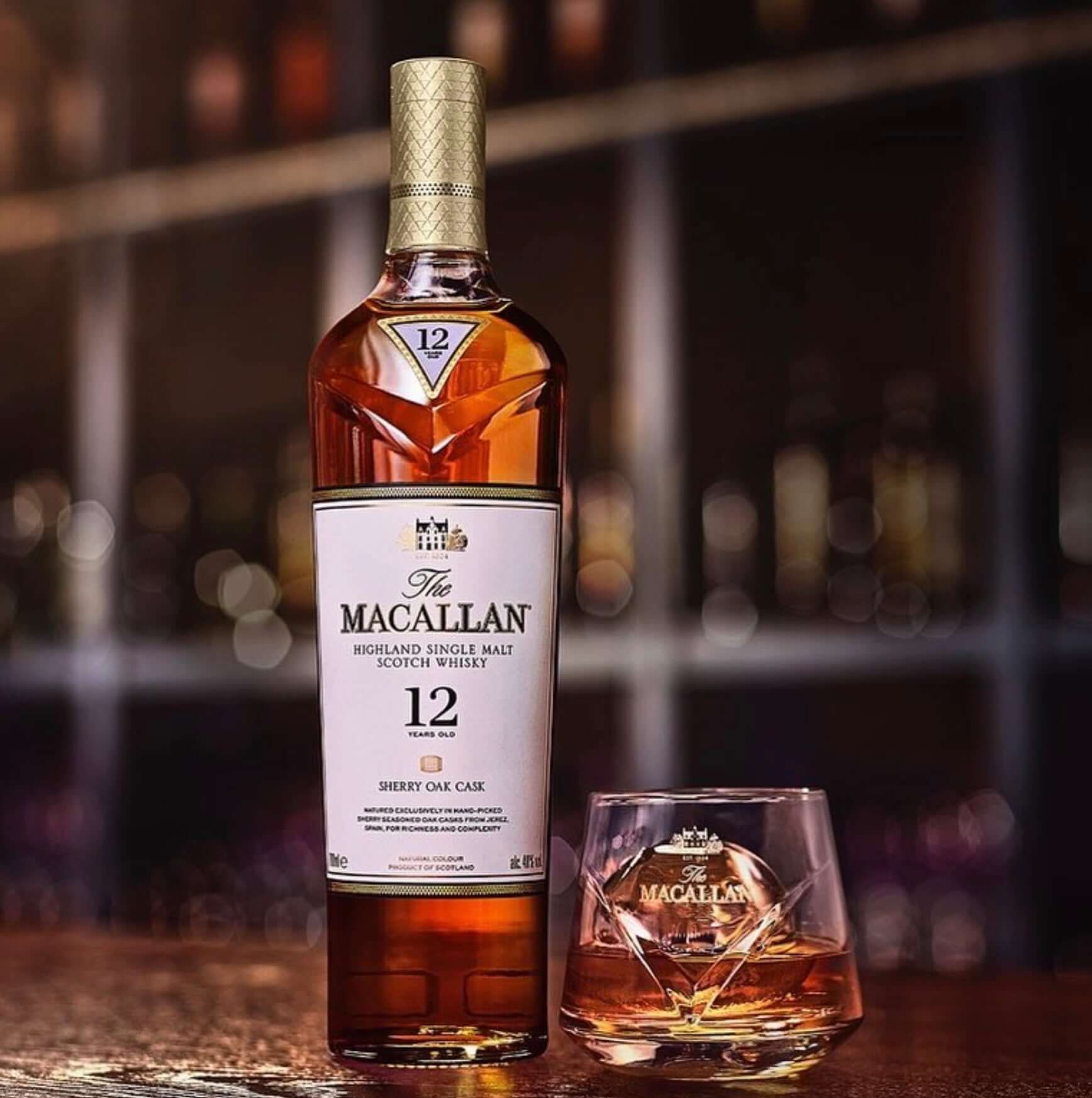 The Macallan Sherry Oak 12 Year, rich gold whisky bottle with glass on wooden bar, showcasing its elegance and complexity.