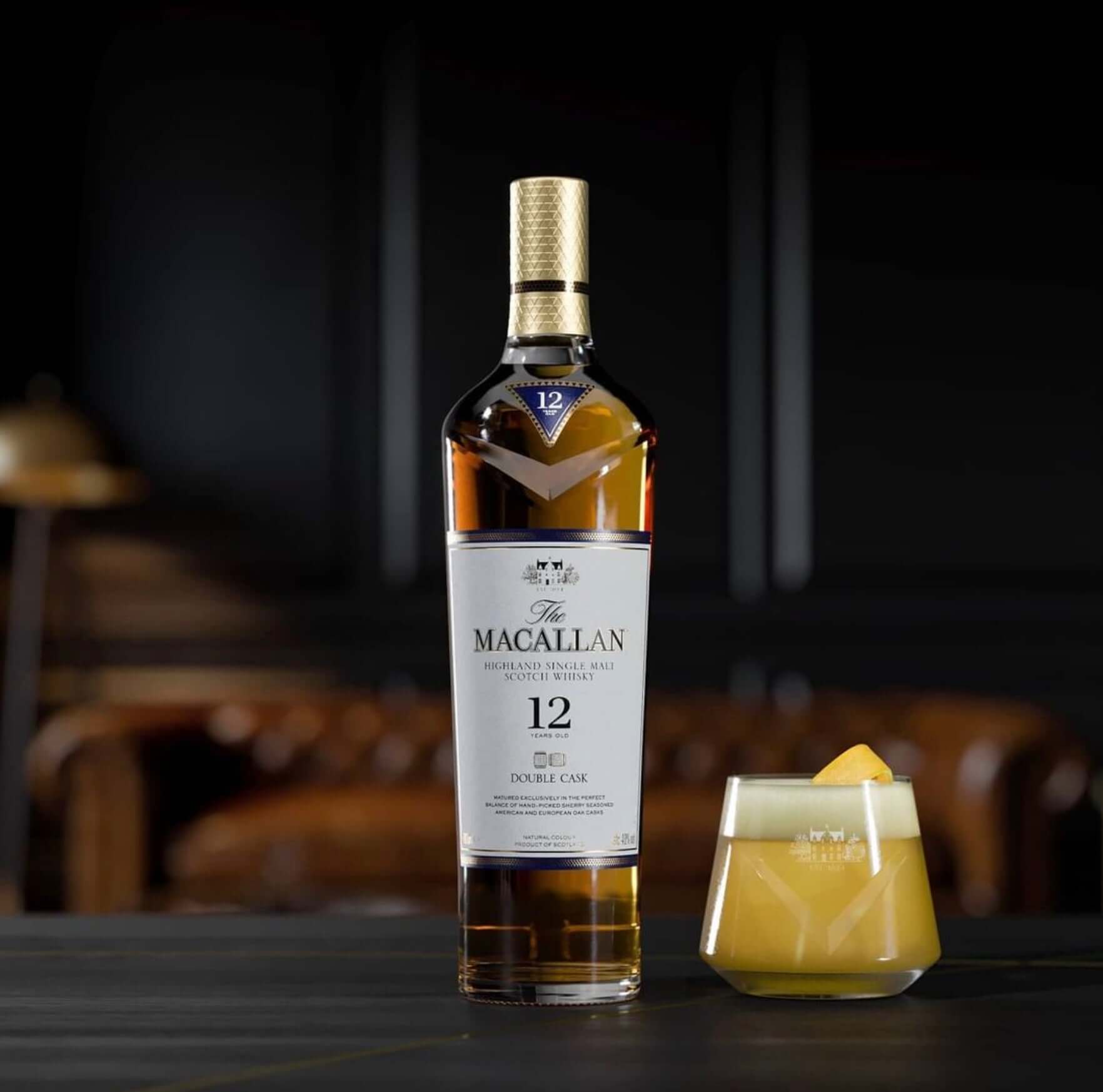 The Macallan Double Cask 12 Year bottle with a citrus cocktail on a wooden table, highlighting the brand's elegance.
