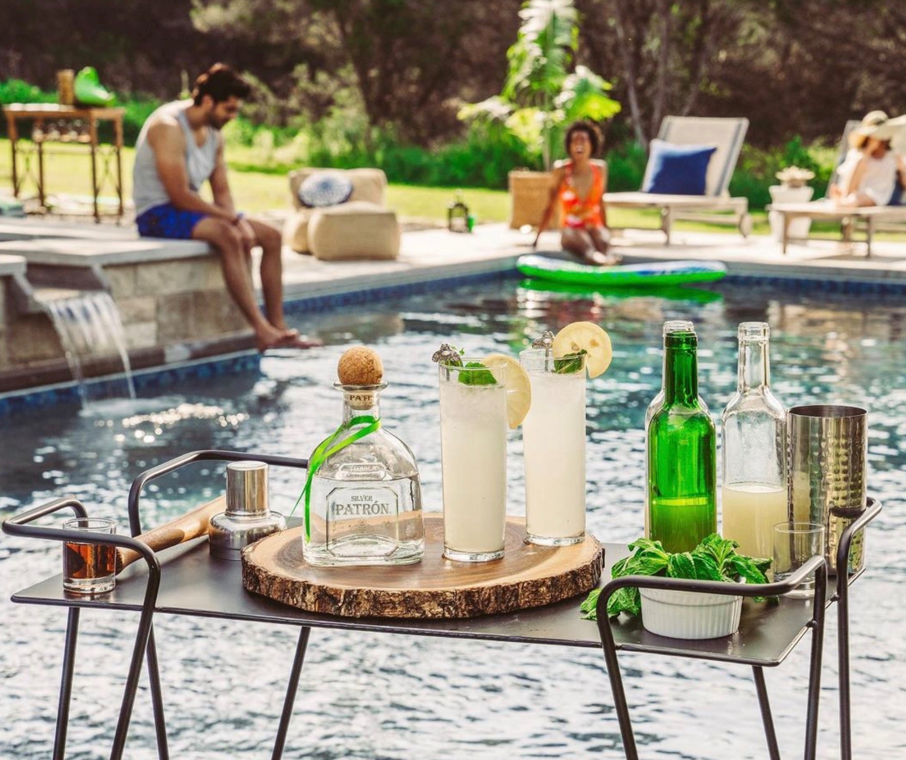 Refreshing cocktails featuring Patrón Silver Tequila by a poolside, surrounded by friends and a serene outdoor setting.