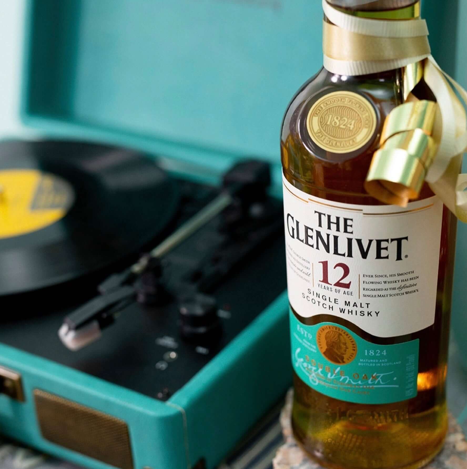 The Glenlivet 12 Year Old single malt Scotch whisky bottle beside a vintage record player.