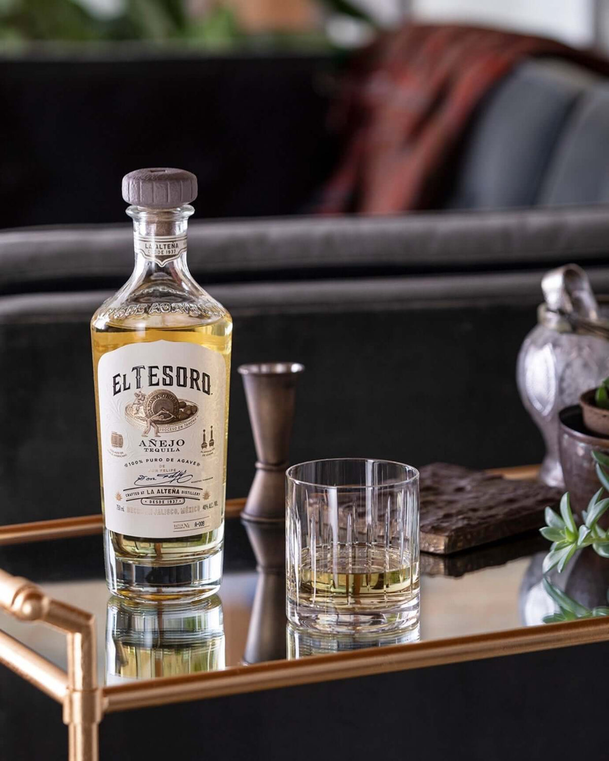 El Tesoro Añejo tequila bottle and glass on a stylish table, showcasing its golden color and elegant design.