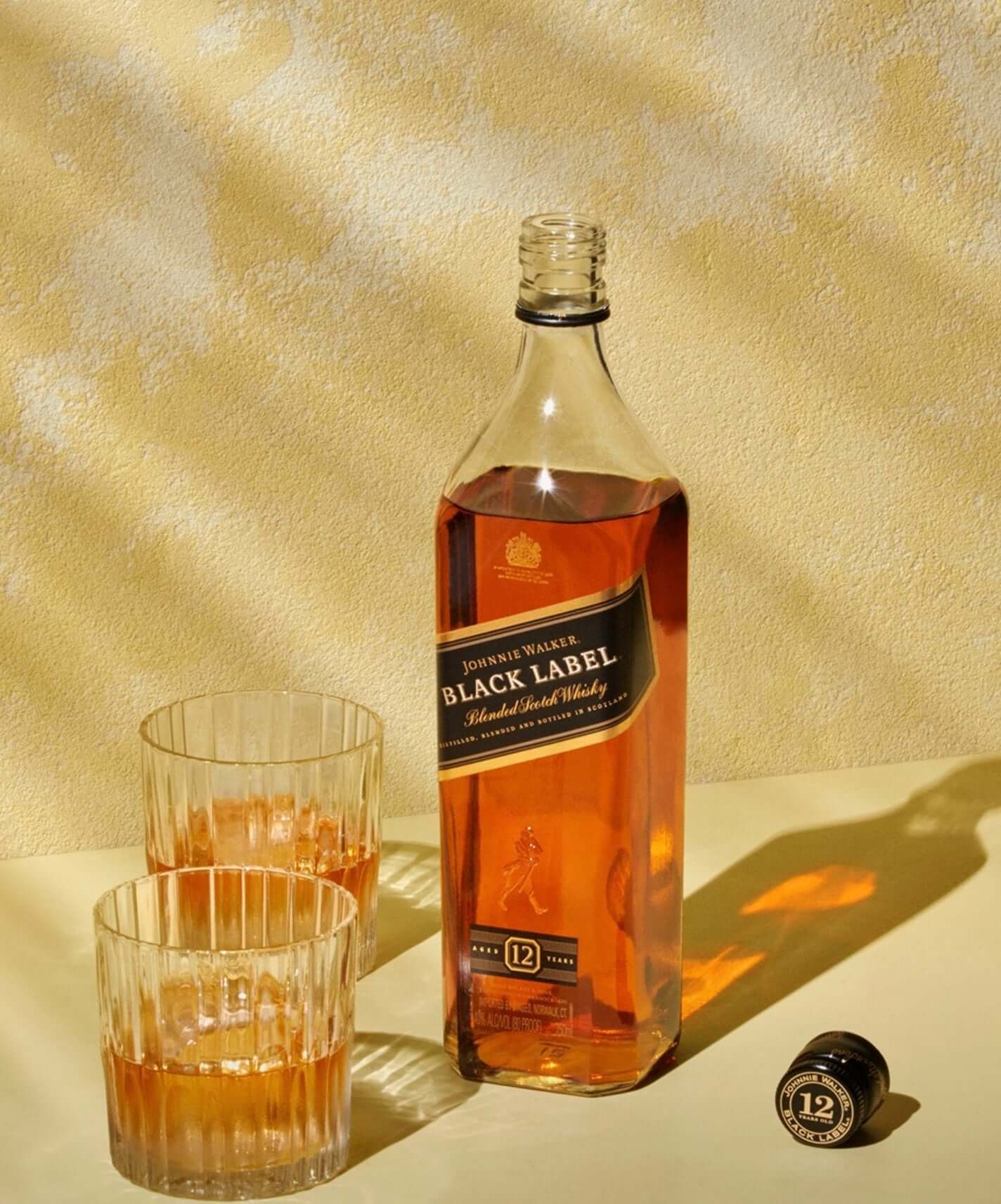 Johnnie Walker Black Label whisky bottle with two glasses, showcasing its rich amber color and 12-year aging.
