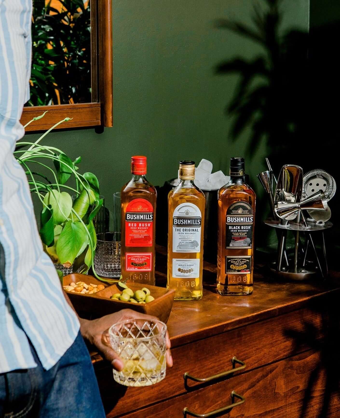 Bushmills Black Bush Irish Whiskey alongside other Bushmills bottles on a stylish wooden countertop.