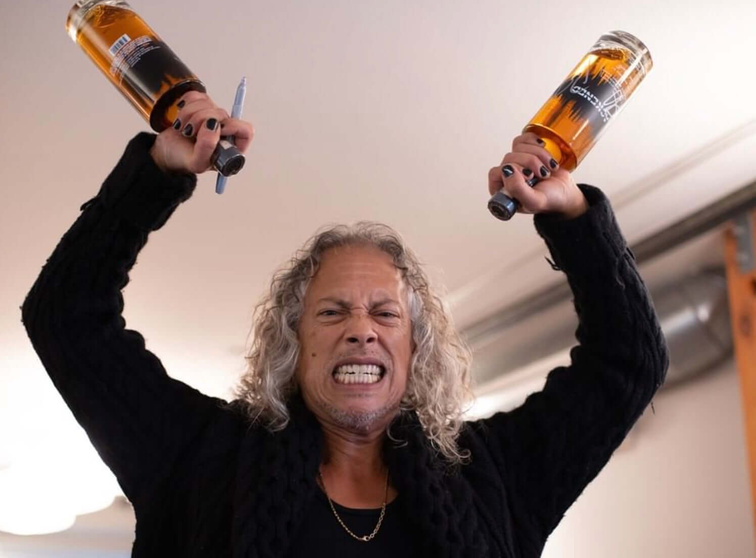 Metallica collaborator holding two bottles of Blackened American Whiskey, showcasing the super-premium spirit.