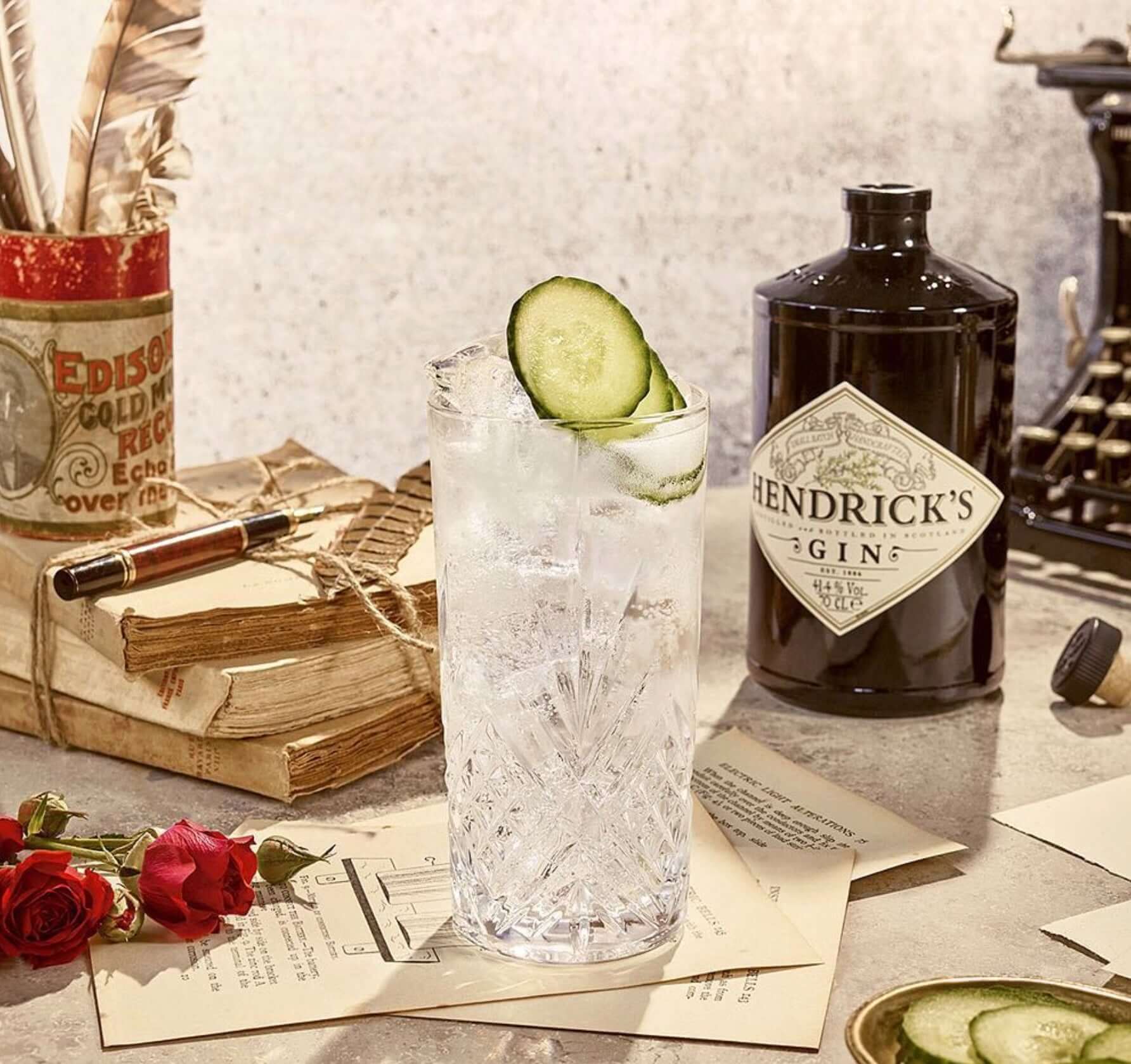 Refreshing Hendrick's Gin cocktail with cucumber garnish, surrounded by vintage decor and books.