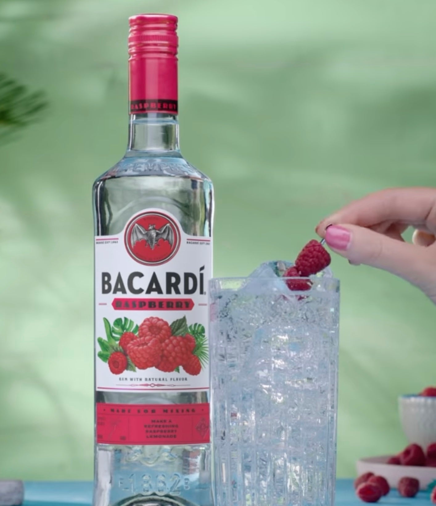 Bacardí Raspberry Rum bottle with a refreshing cocktail and fresh raspberries, showcasing tropical flavors.