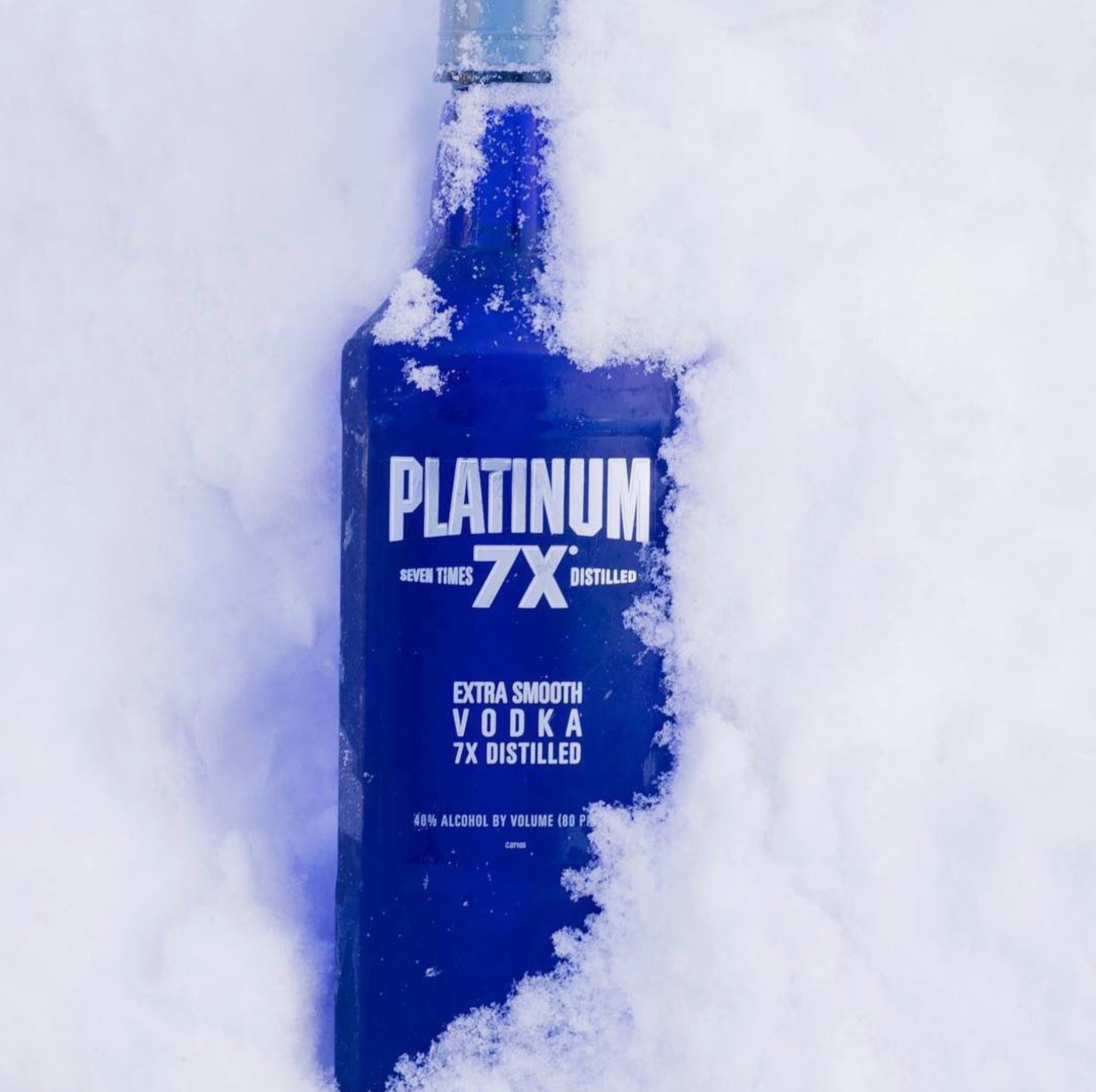 Platinum 7X Vodka in blue bottle, showcasing its ultra-smooth, seven times distilled quality in snow.