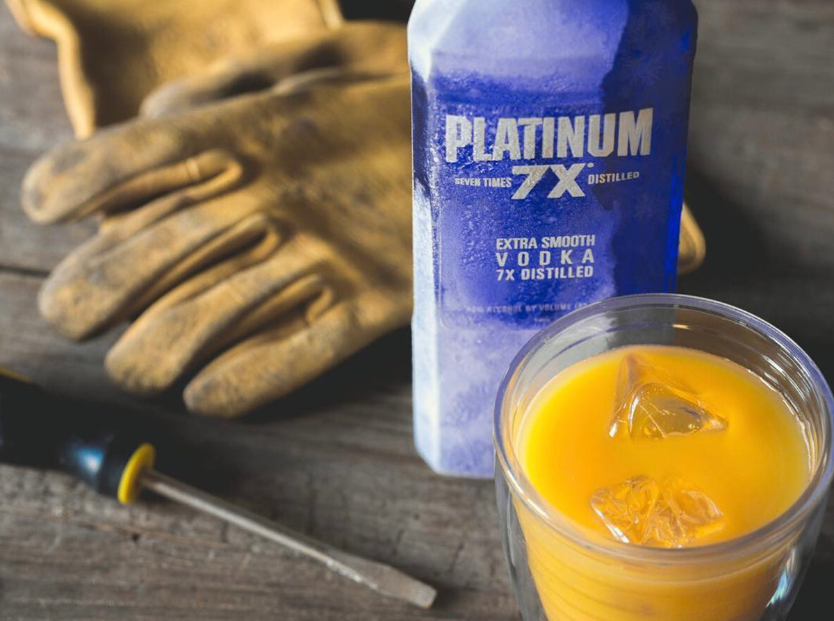 Platinum 7x Vodka bottle next to gloves and a cocktail in a glass with ice.