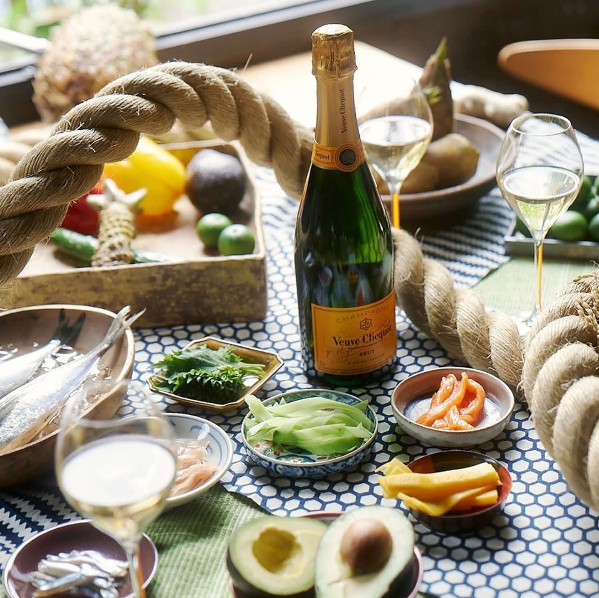 Veuve Clicquot Brut Champagne on a table with fresh fruits and seafood, surrounded by elegant glassware.