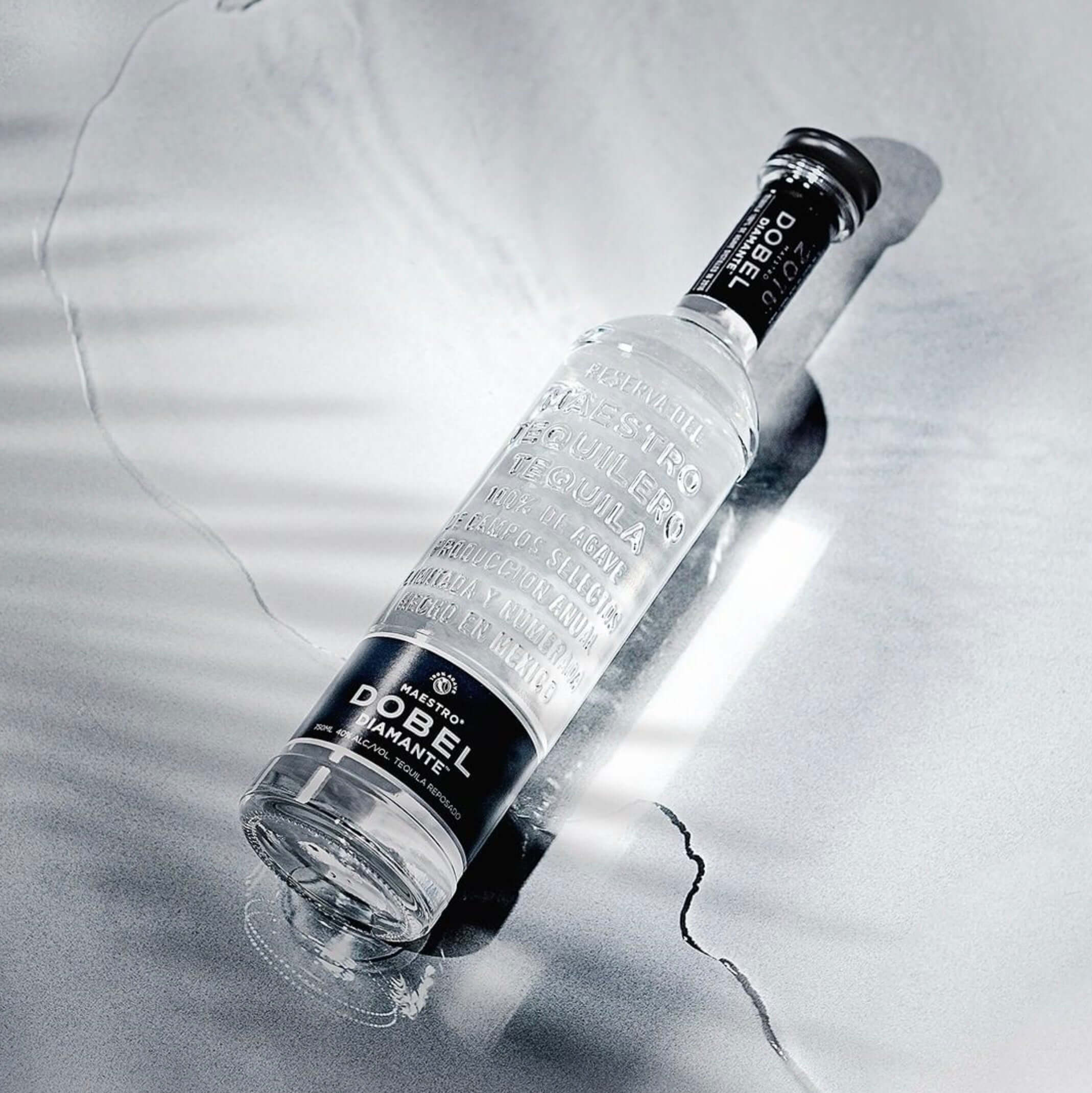 Bottle of Maestro Dobel Diamante Tequila on a reflective surface, showcasing its clarity and elegance.