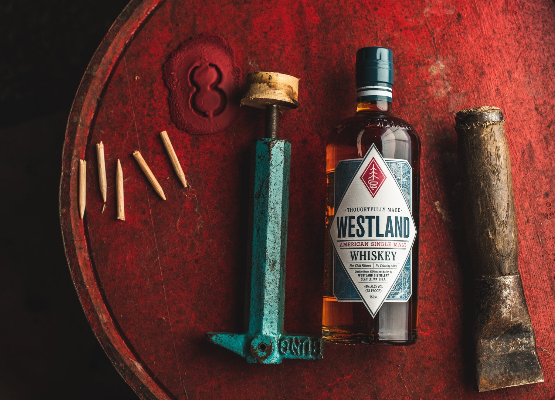 Westland Single Malt Whiskey bottle on a rustic table with tools and filler sticks.