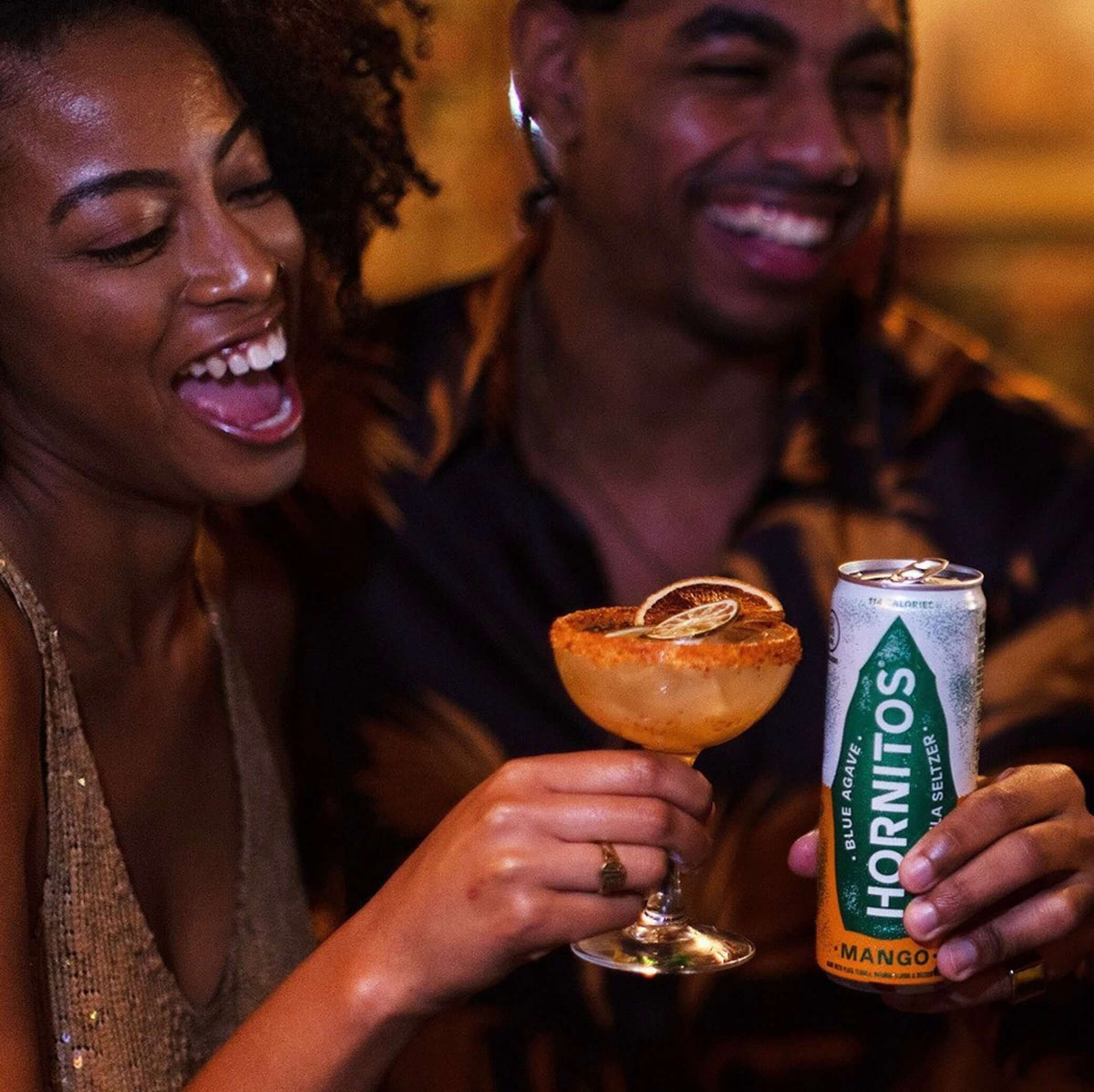 Two friends enjoying Hornitos Mango Tequila Seltzer can and cocktail, celebrating a fun night together.