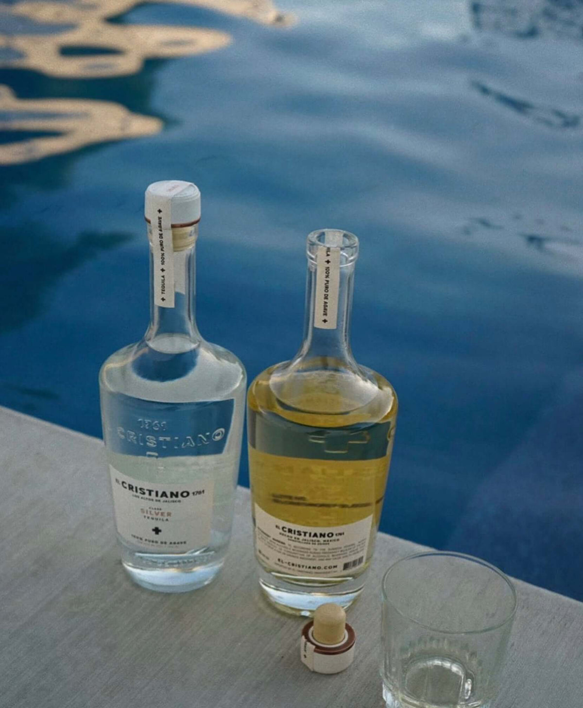 El Cristiano 1761 Silver Tequila bottles displayed by a poolside, showcasing premium quality and elegance.