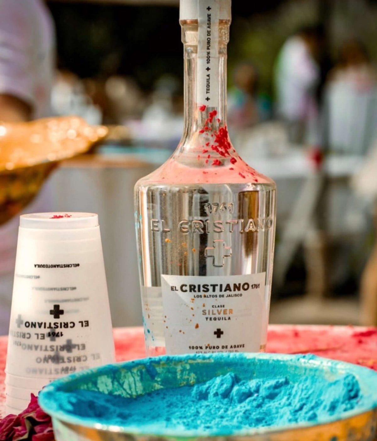 El Cristiano 1761 silver tequila bottle with vibrant blue and decorative powders.