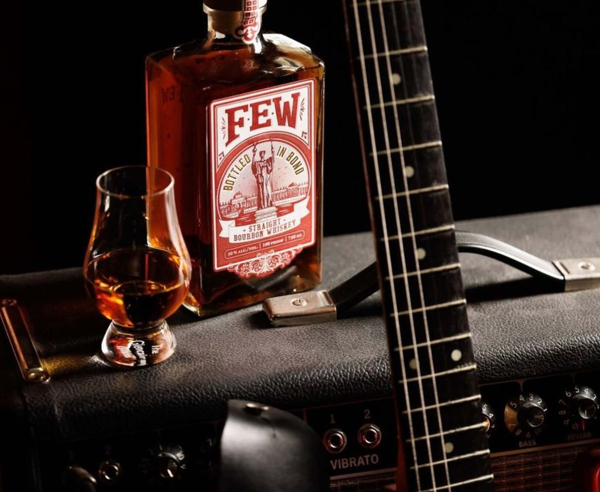 FEW Bottled in Bond Bourbon with a glass of whiskey, guitar, and amplifier in a cozy setting.