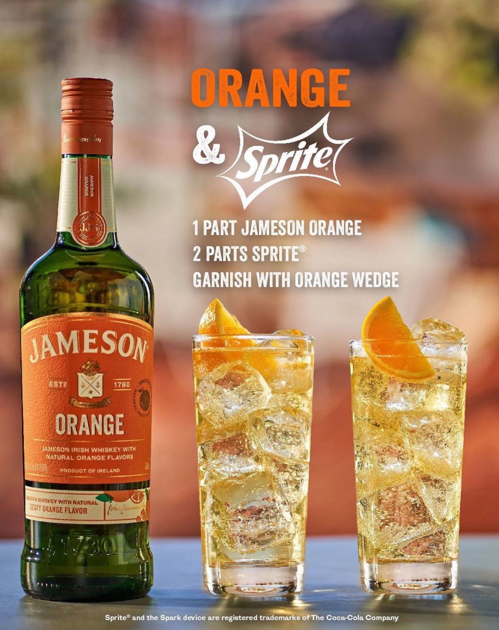 Jameson Orange Irish Whiskey bottle next to two glasses mixed with Sprite and garnished with orange wedges.