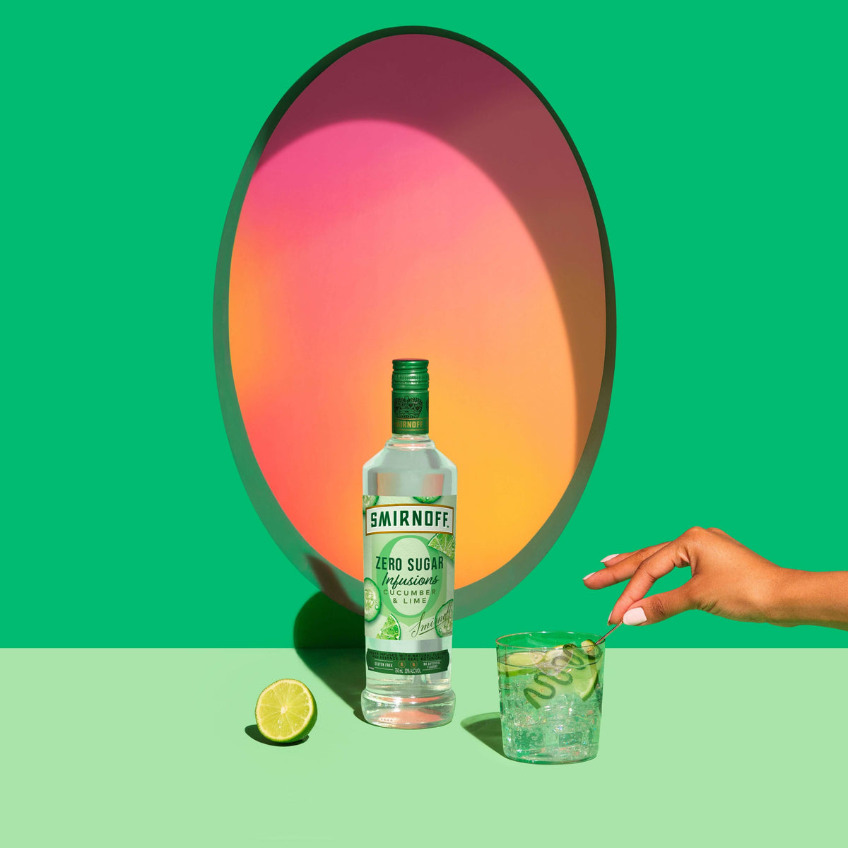 Smirnoff Zero Sugar Infusions Cucumber & Lime bottle with a cocktail and lime against a vibrant green backdrop.