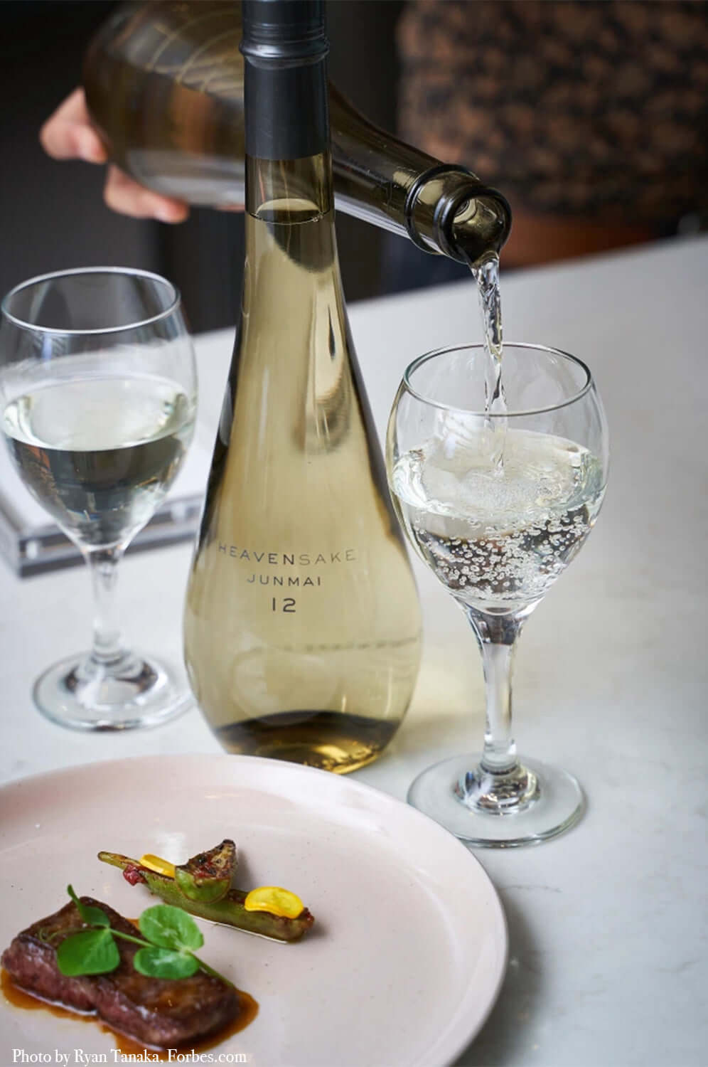 Heavensake Konishi Junmai 12 sake being poured into a glass, paired with a delicious dish.