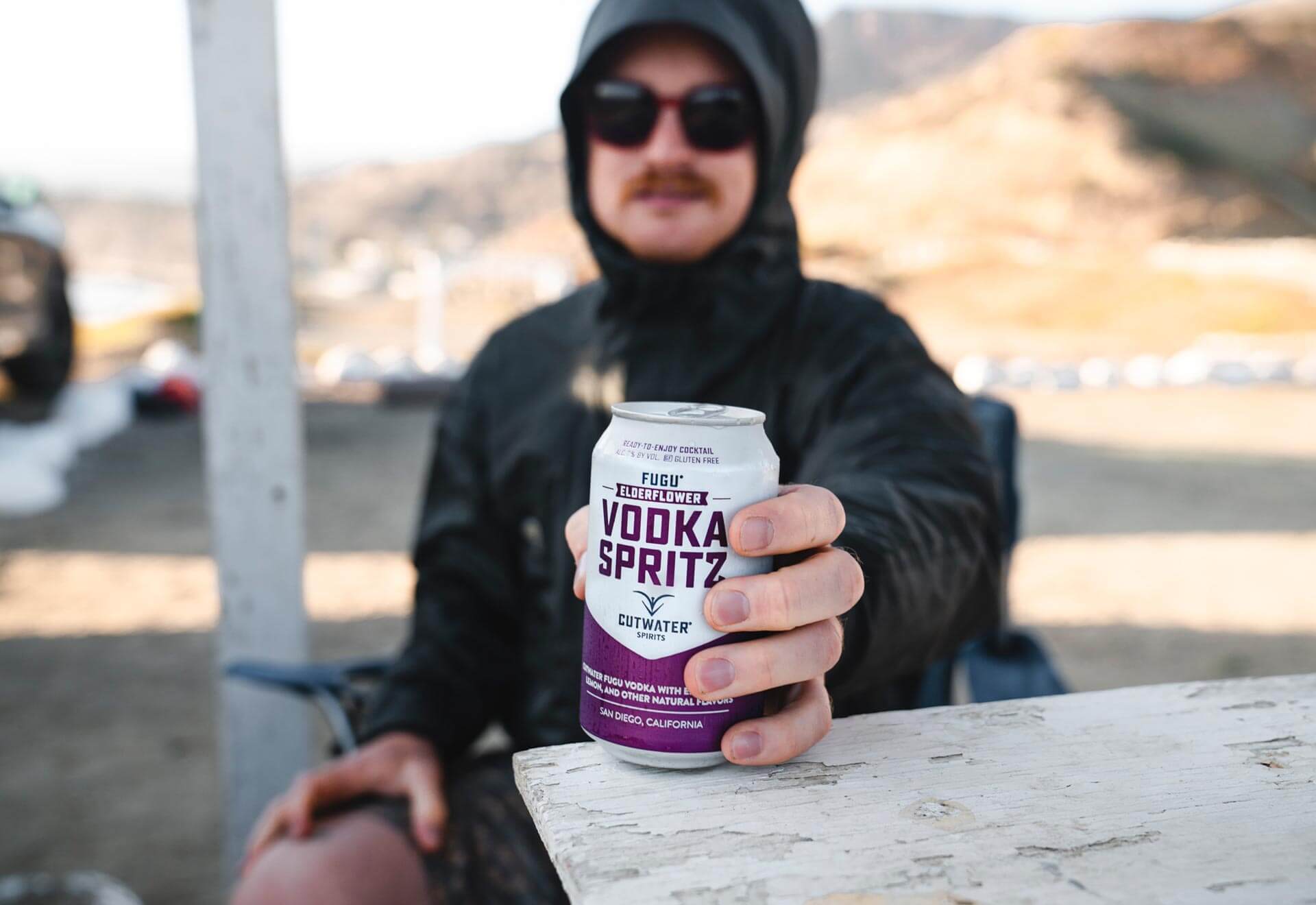 Person holding Cutwater Vodka Spritz can outdoors, showcasing the refreshing drink in a casual setting.