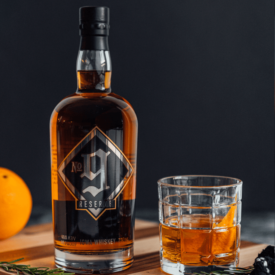Slipknot No. 9 Iowa Reserve Whiskey bottle with glass and orange, showcasing rich amber color and bold flavors.