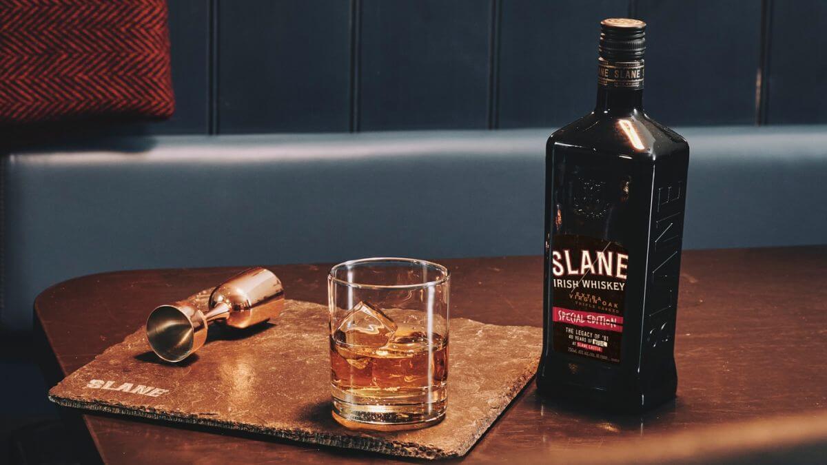 Slane Irish Whiskey Special Edition bottle with a glass of whiskey on a slate coaster in an elegant setting.
