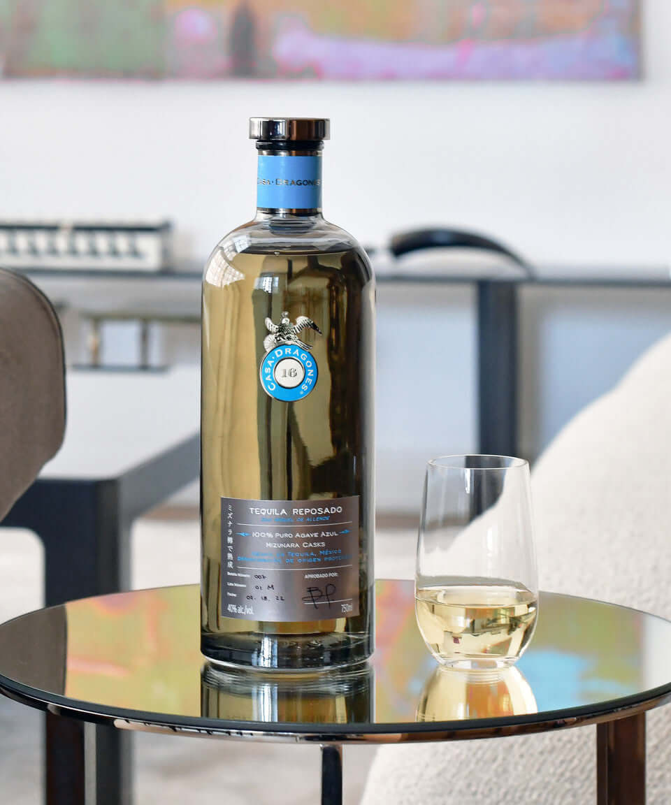 Casa Dragones Reposado Mizunara tequila bottle with glass on a stylish table, showcasing its elegant design.