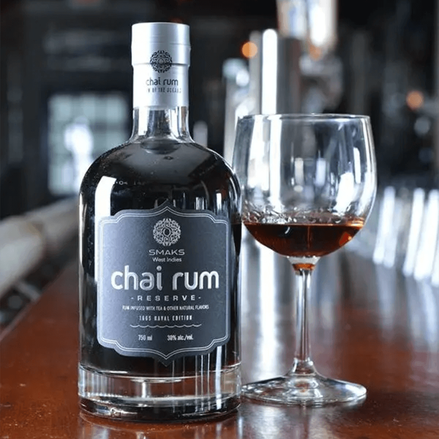 Akal Chai Reserve 1665 Naval Edition Rum bottle next to a glass, showcasing its rich color and luxurious design.