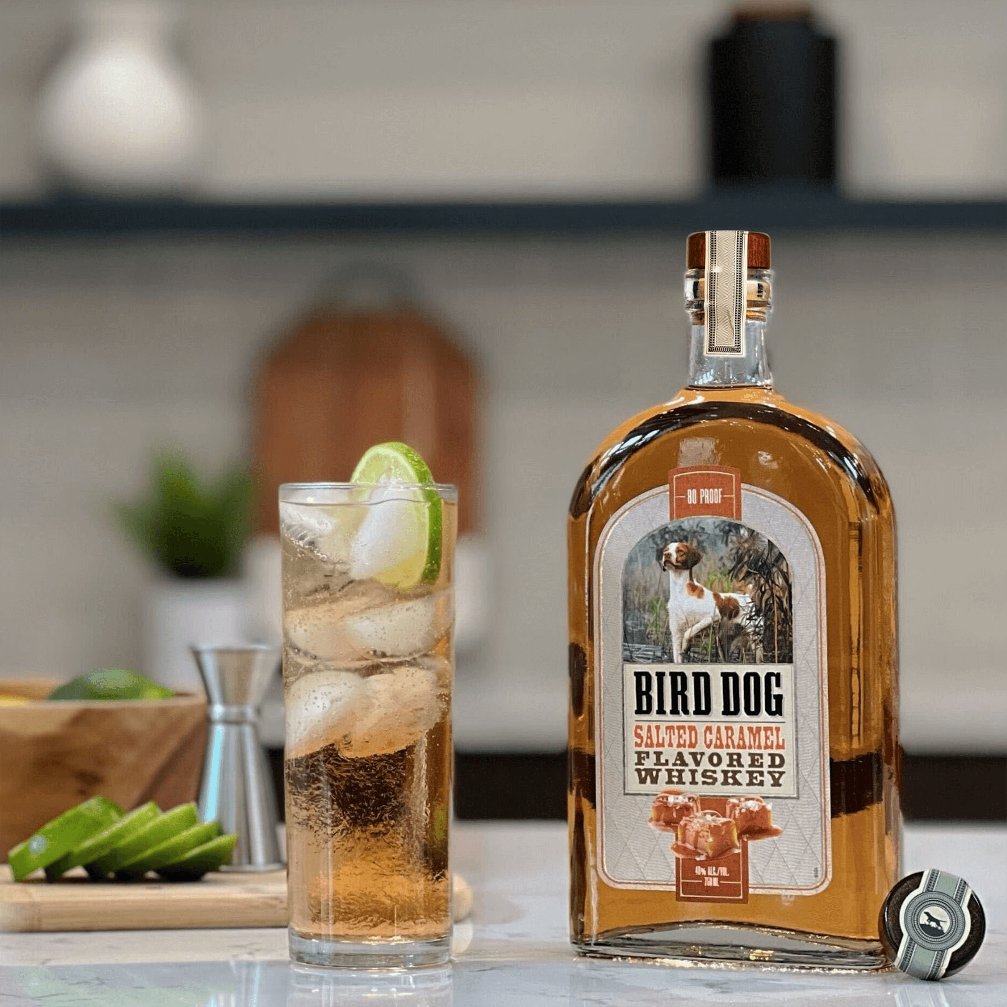 Bird Dog Salted Caramel Whiskey bottle with cocktail and ice, showcasing a sweet bourbon perfect for after meals.