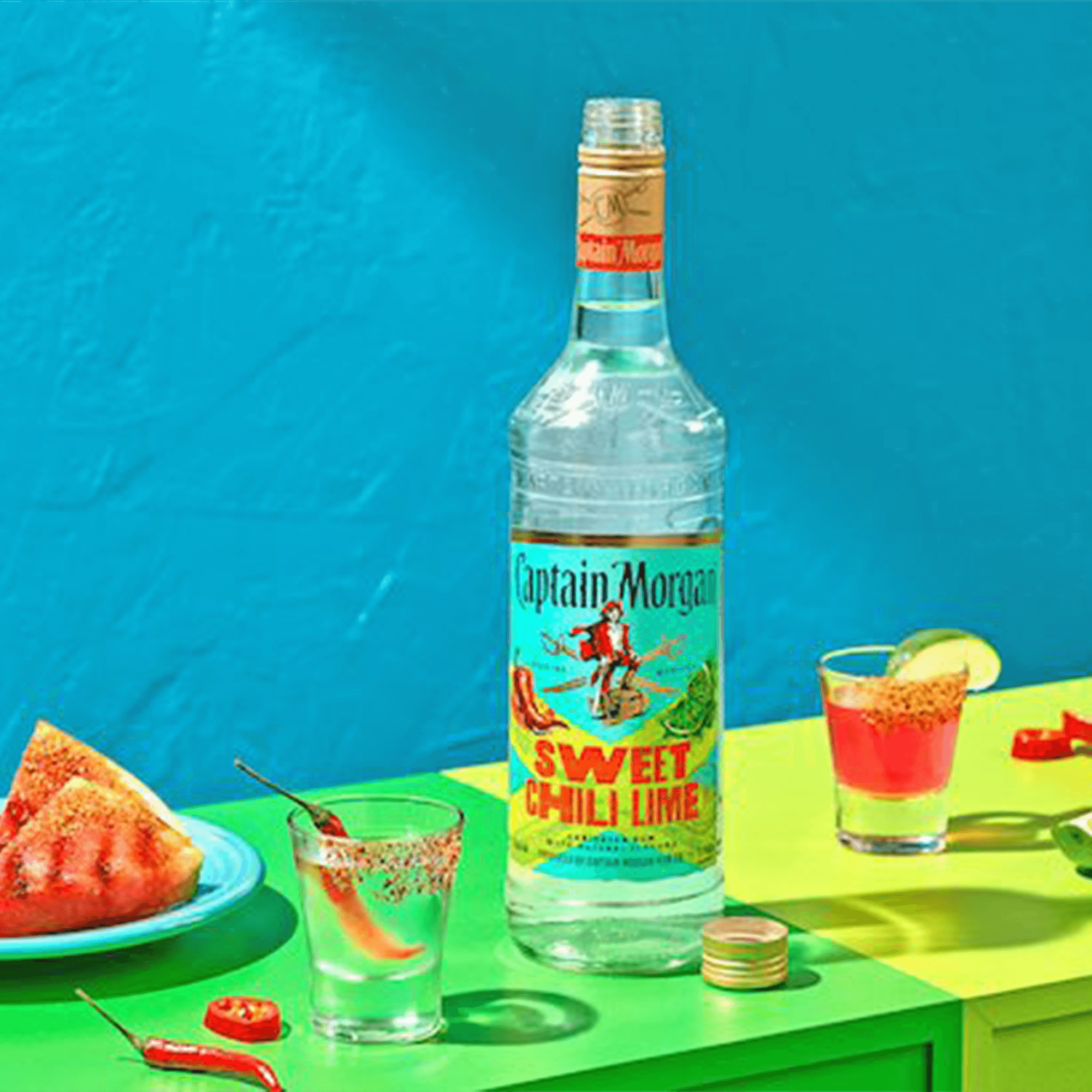 Captain Morgan Sweet Chili Lime rum bottle with cocktails and fresh ingredients on a vibrant background.
