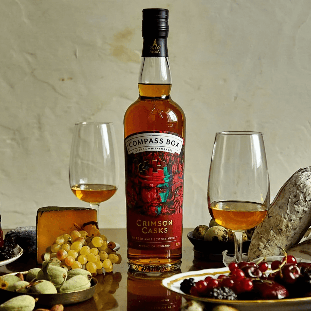 Compass Box Crimson Casks Blended Malt Scotch Whisky bottle with glasses and gourmet food on a table.