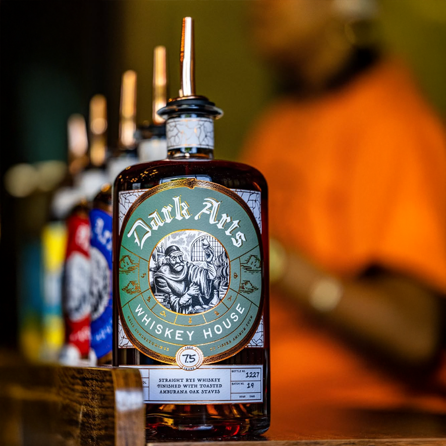 Dark Arts 7 Year Amburana Oak Staves Rye Whiskey bottle showcasing unique design and label in a bar setting.