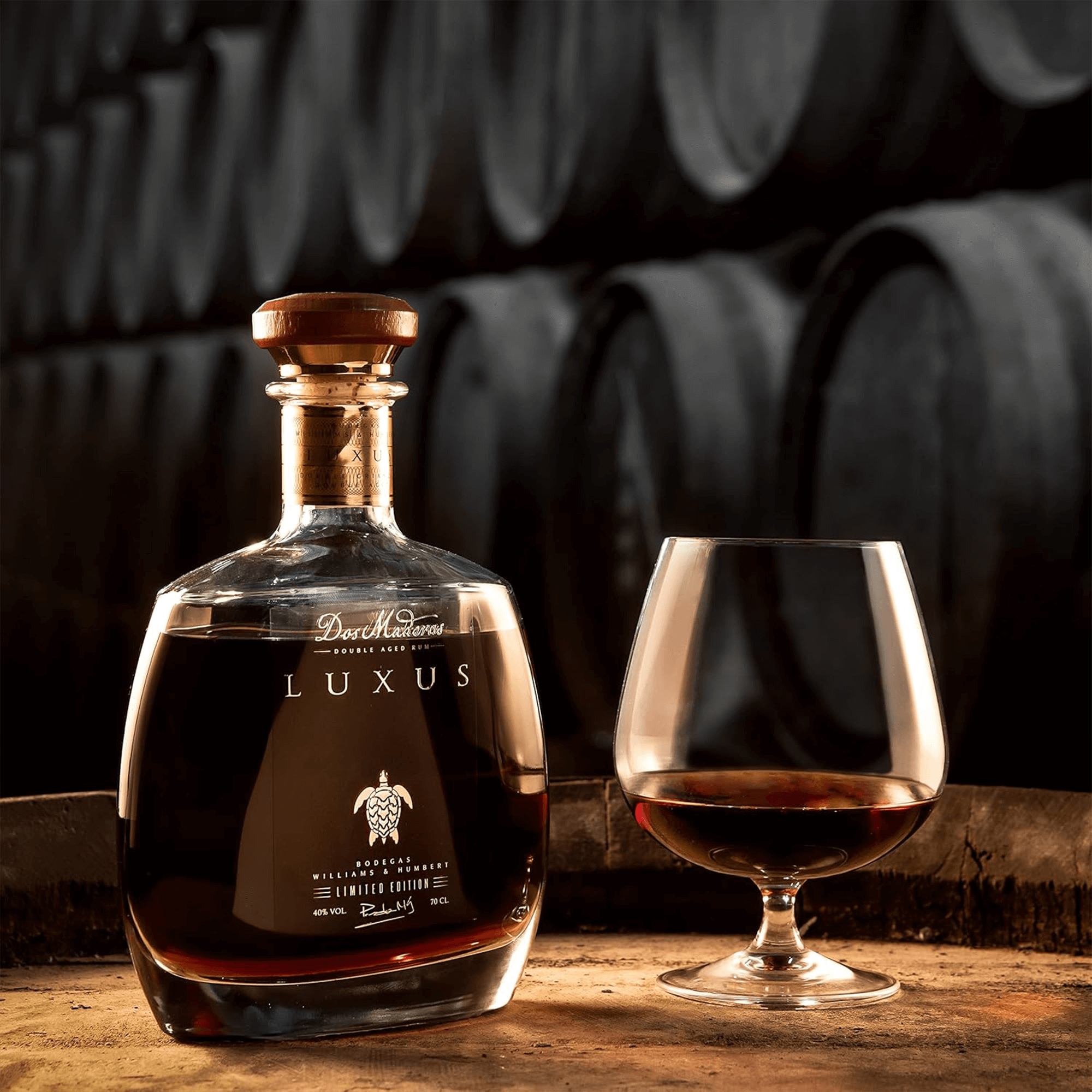 Dos Maderas Luxus Double Aged Rum 700ml in a glass, showcasing its rich color and elegant design against a barrel backdrop.