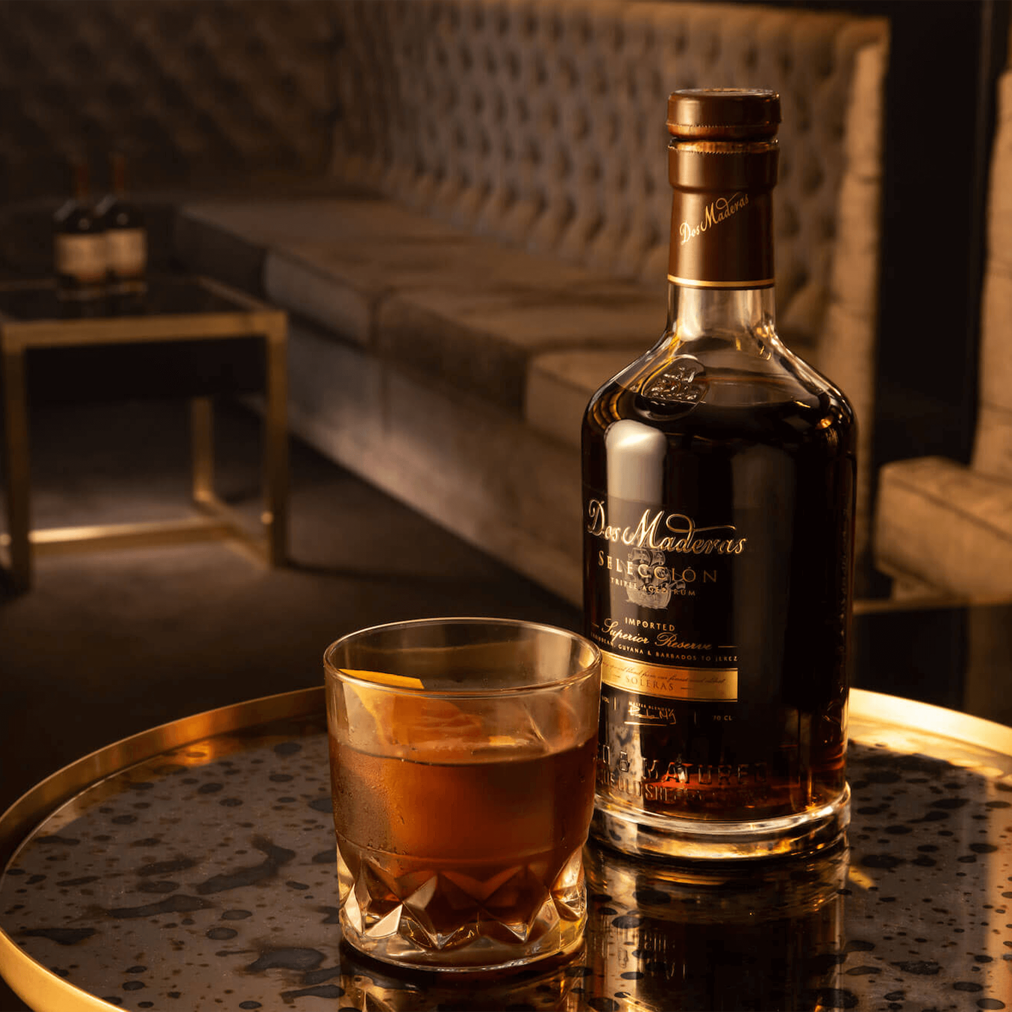 Dos Maderas Selecction Triple Aged Soleras Rum bottle with a glass on a table, showcasing rich colors and elegant setting.