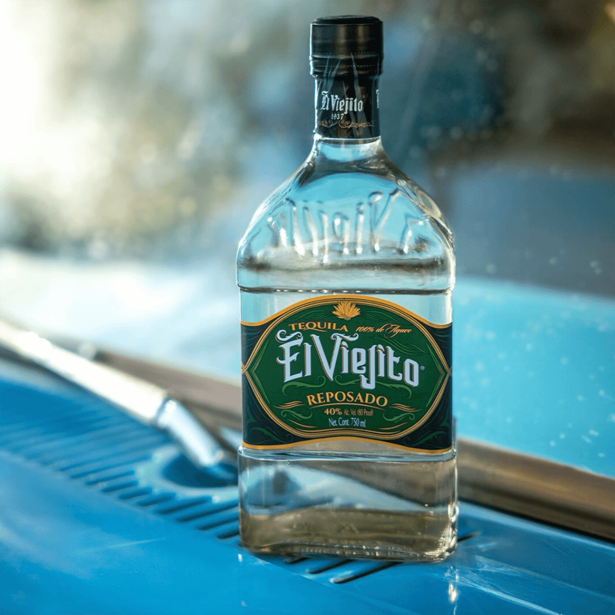 El Viejito Reposado Tequila bottle on a vintage blue surface, showcasing its rich heritage and smooth character.