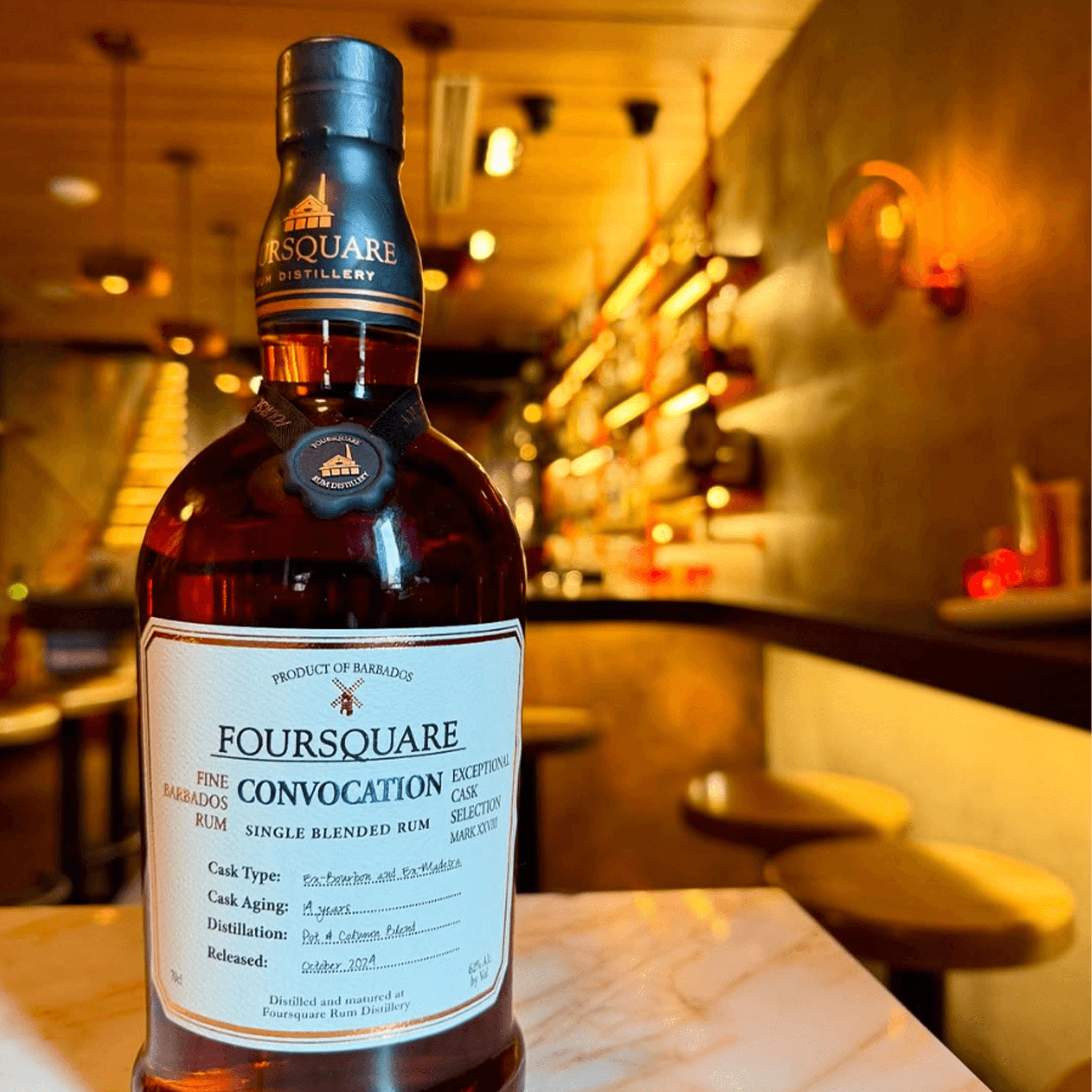 Foursquare Exceptional Cask Selection Mark XXVIII Convocation Rum bottle on a bar with warm lighting.