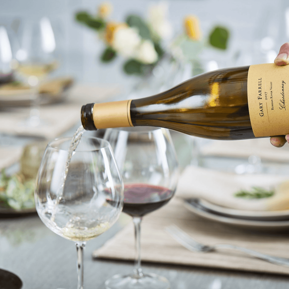 Pouring Gary Farrell Russian River Valley Chardonnay into a glass on a beautifully set dining table.