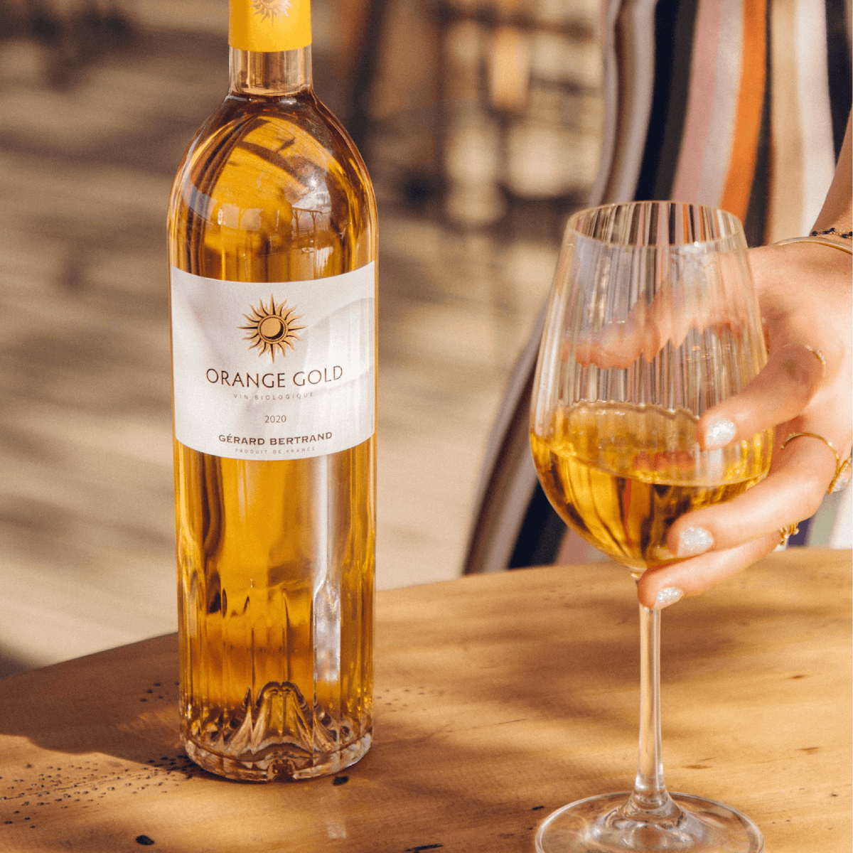 Bottle of Gérard Bertrand Orange Gold wine with glass, showcasing its vibrant orange hue and elegant design.