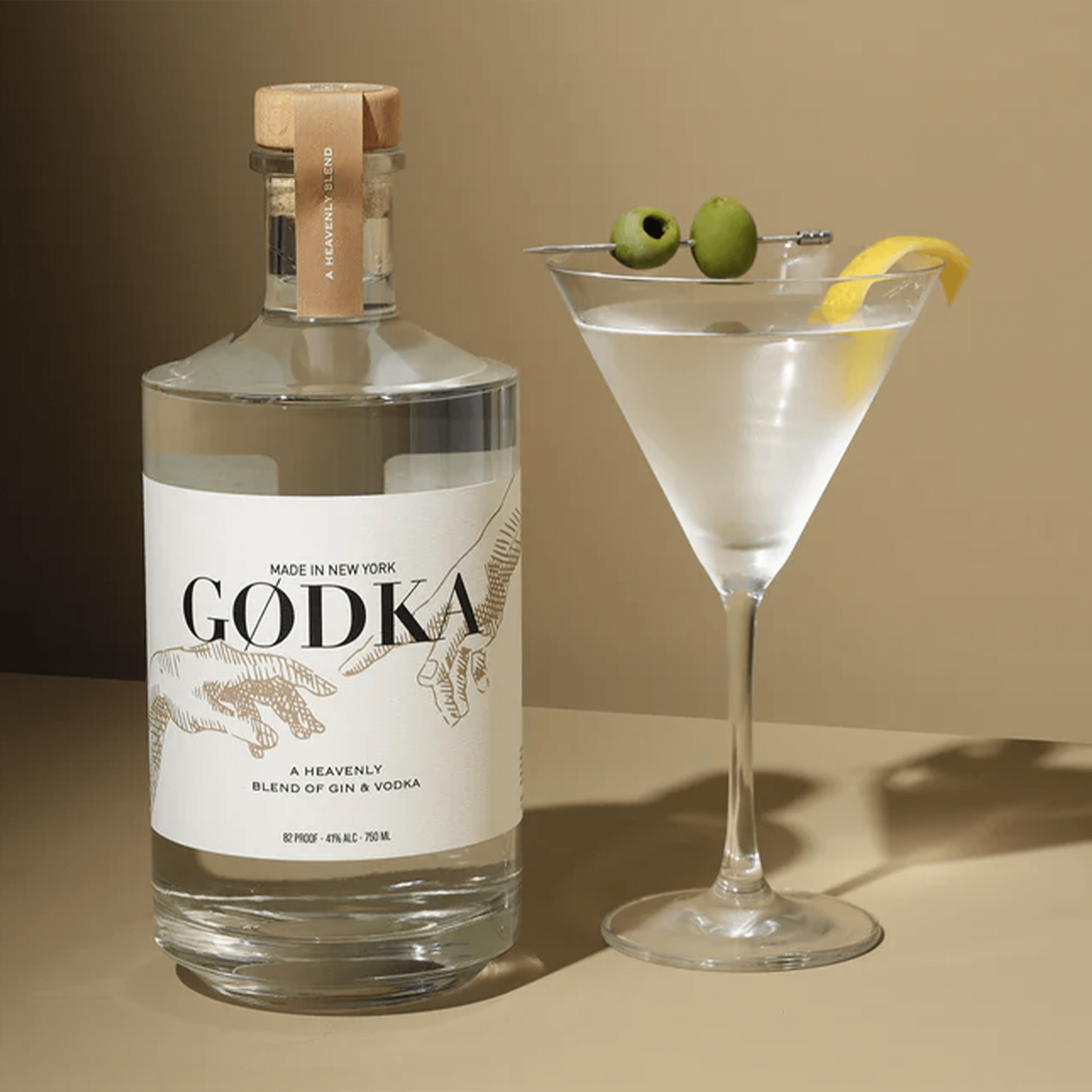 GODKA blend of gin and vodka bottle next to a elegant cocktail garnished with olives and lemon