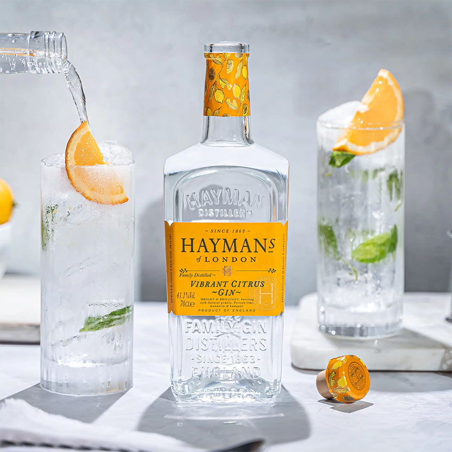 Hayman's Vibrant Citrus Gin bottle surrounded by refreshing cocktails with citrus garnishes.