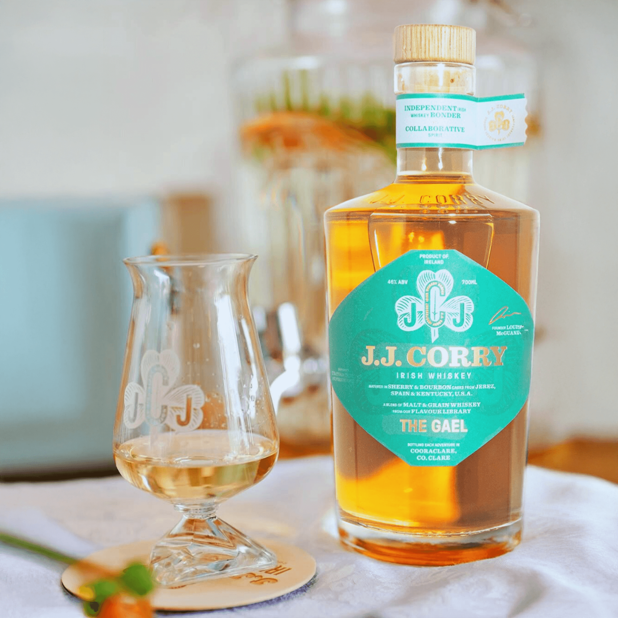 Bottle of JJ Corry The Gael Irish Whiskey beside a glass, showcasing its rich amber color and elegant packaging.