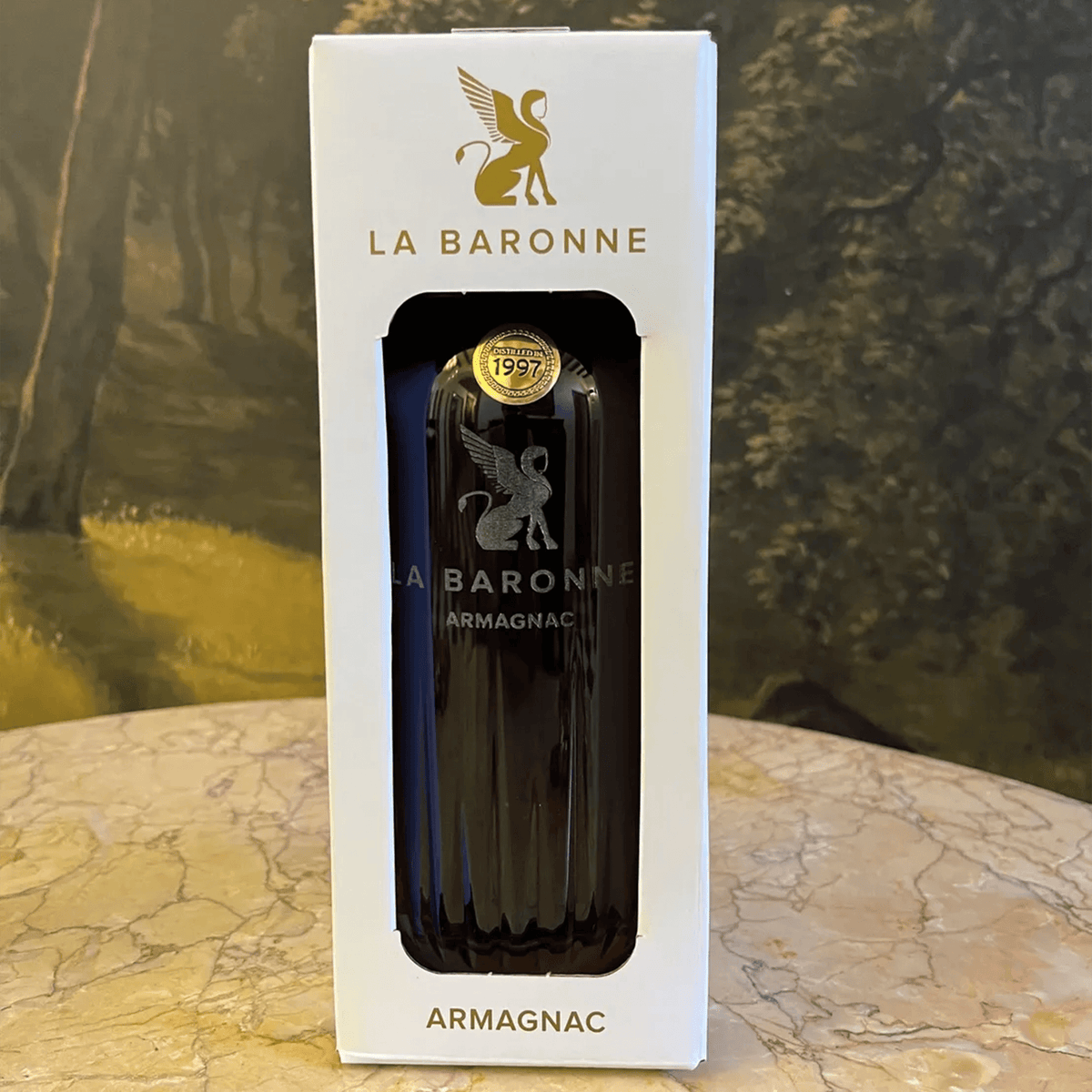 La Baronne Armagnac 1997 in elegant packaging on a marble surface, showcasing fine aged French spirits.