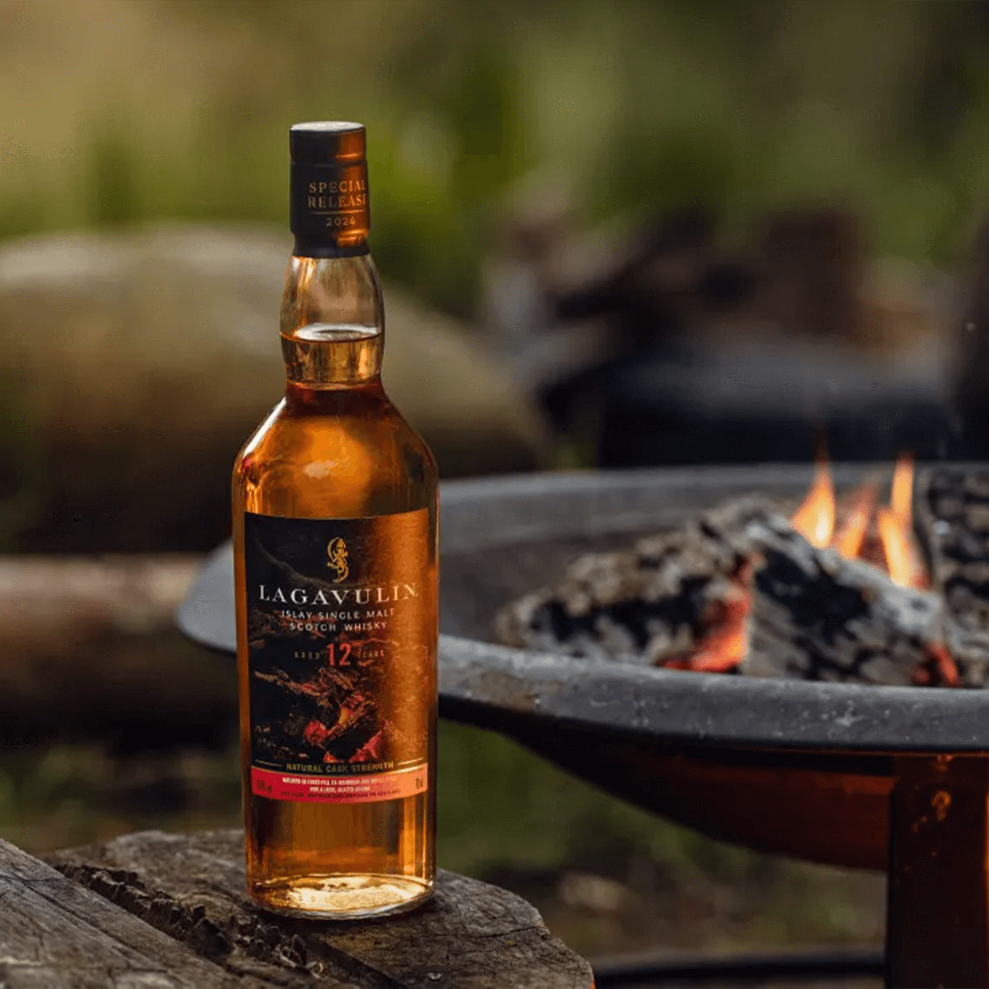 Lagavulin 12 Year Fireside Tales Single Malt Whisky bottle in front of a campfire, showcasing its rich amber color.