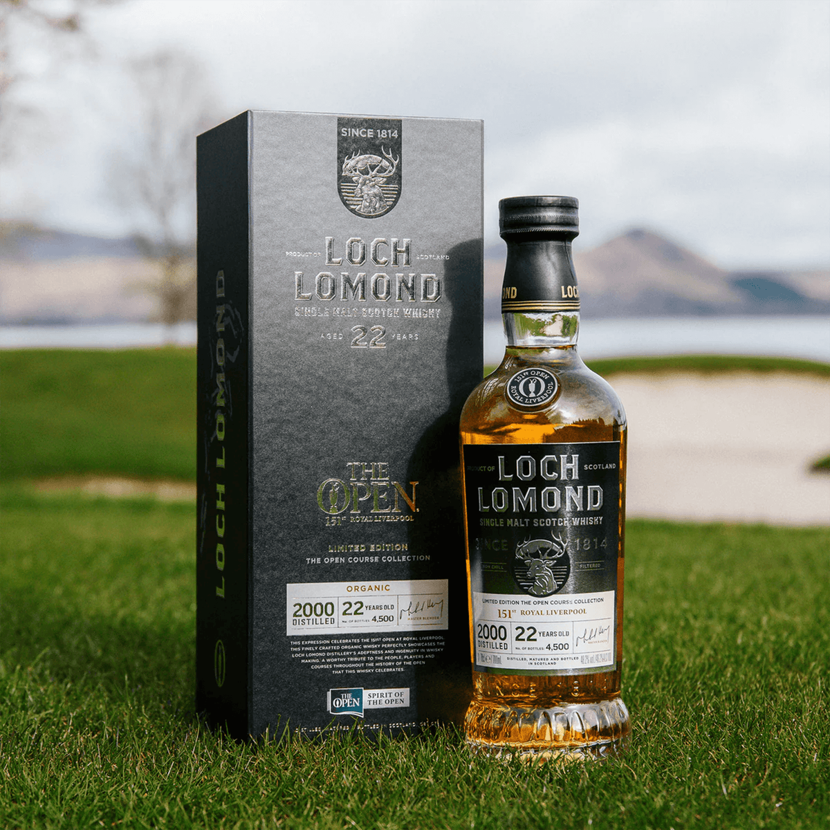 Loch Lomond 22 Year 'The Open' Course Collection 2000 Scotch whisky bottle and box on grass near water.